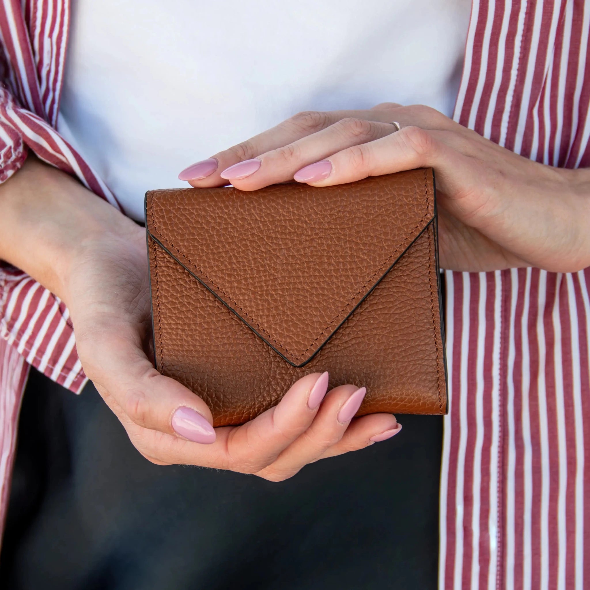 A woman is holding the cognac Italian Pebbled Leather Envelope Wallet