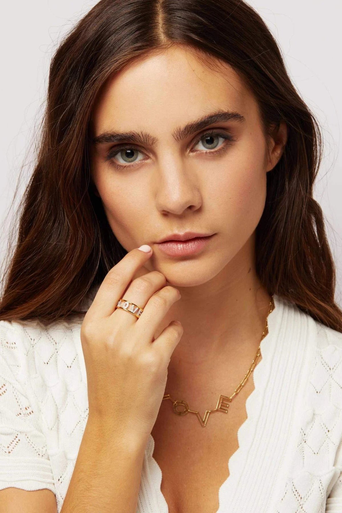 Love Golden Eternity Ring on a model's right hand touching the right side of her chin