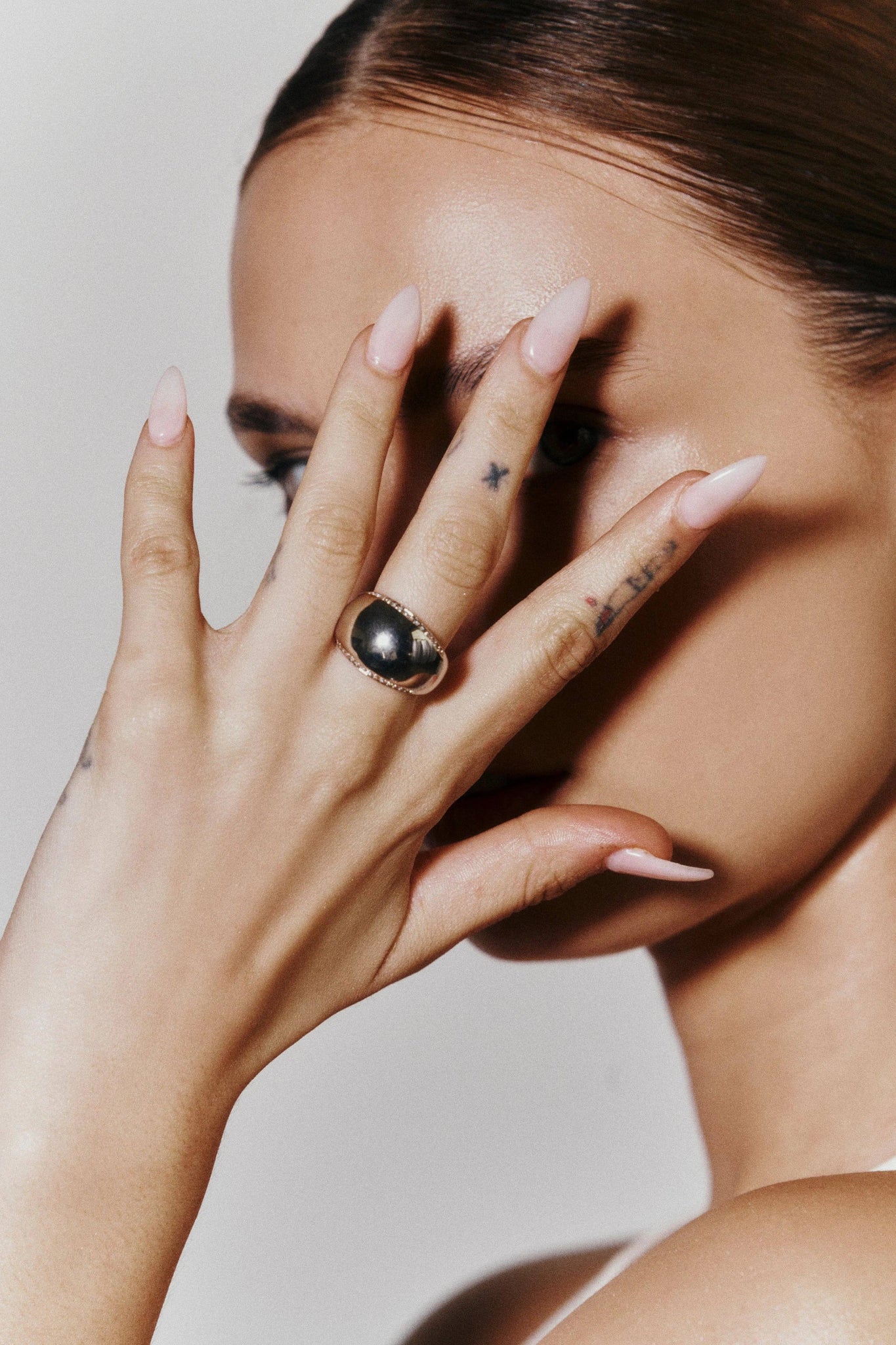 Luxe Pavé Gold Dome Ring on model with her left hand brushed against. the side of her head