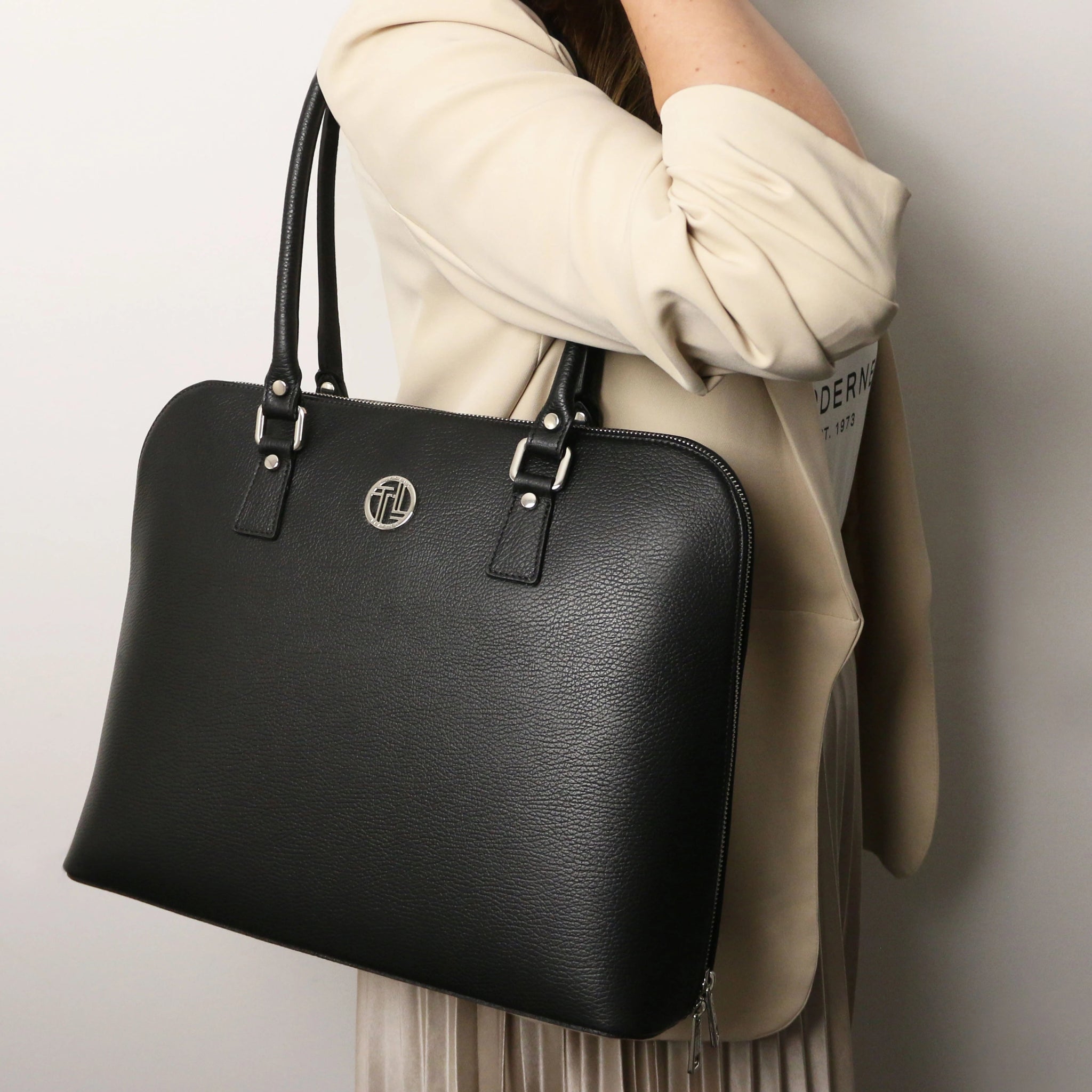A woman is carrying the Magnolia Leather Business Bag in black over her right shoulder