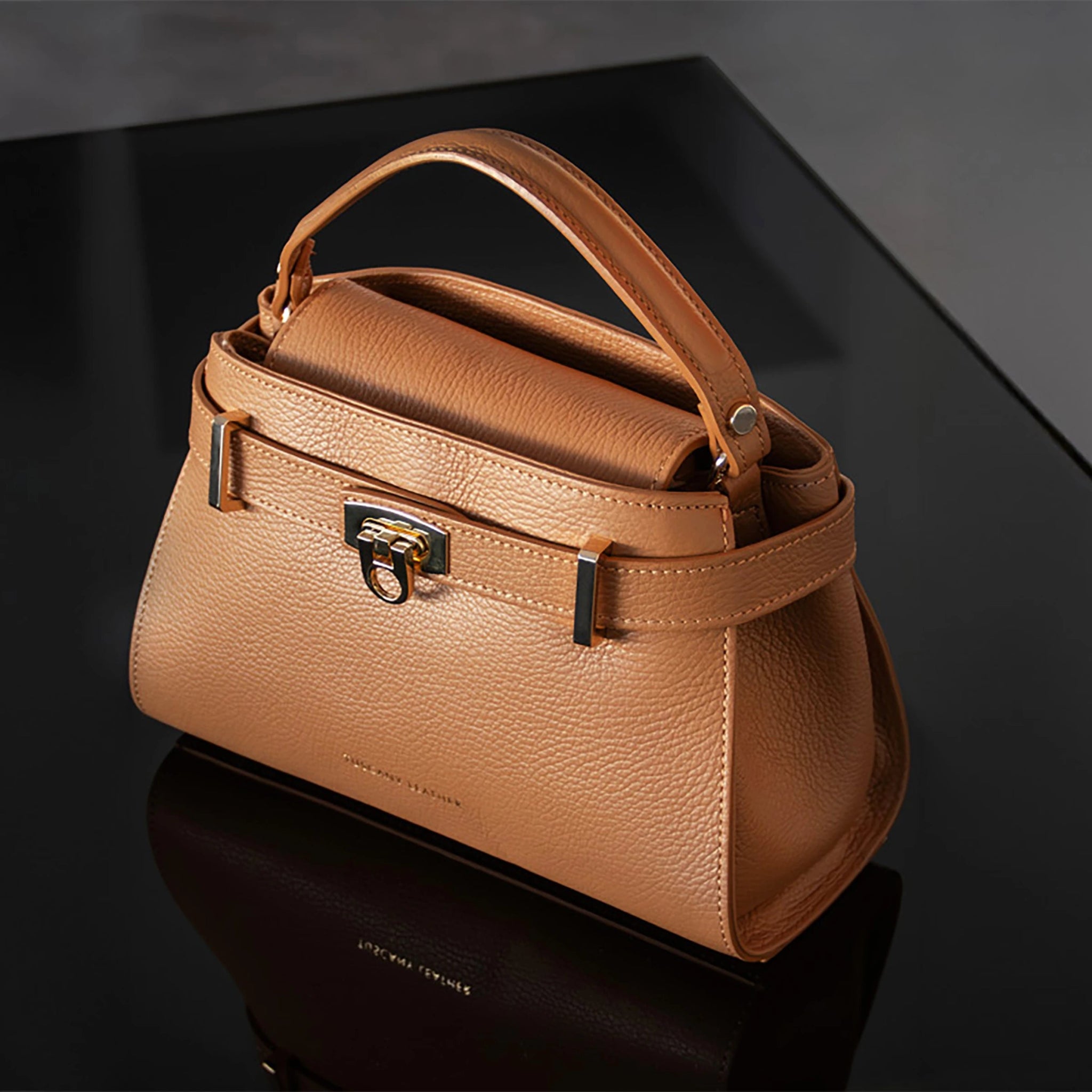 Front view Maisy Italian Leather Small Tote Bag in caramel sitting on a black glass table