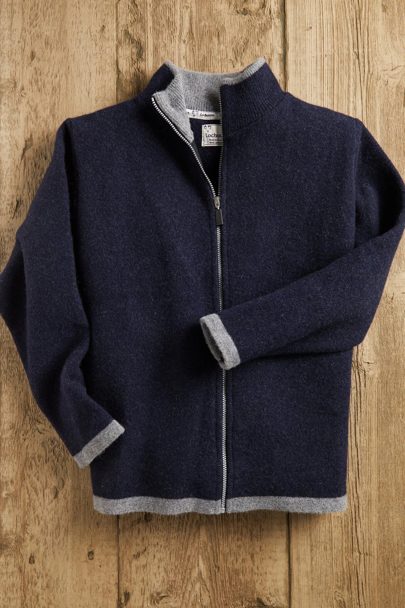 Men's Scottish Borders Felted Wool Cardigan in Navy with zipper opened at top of chest, laying on a wood background
