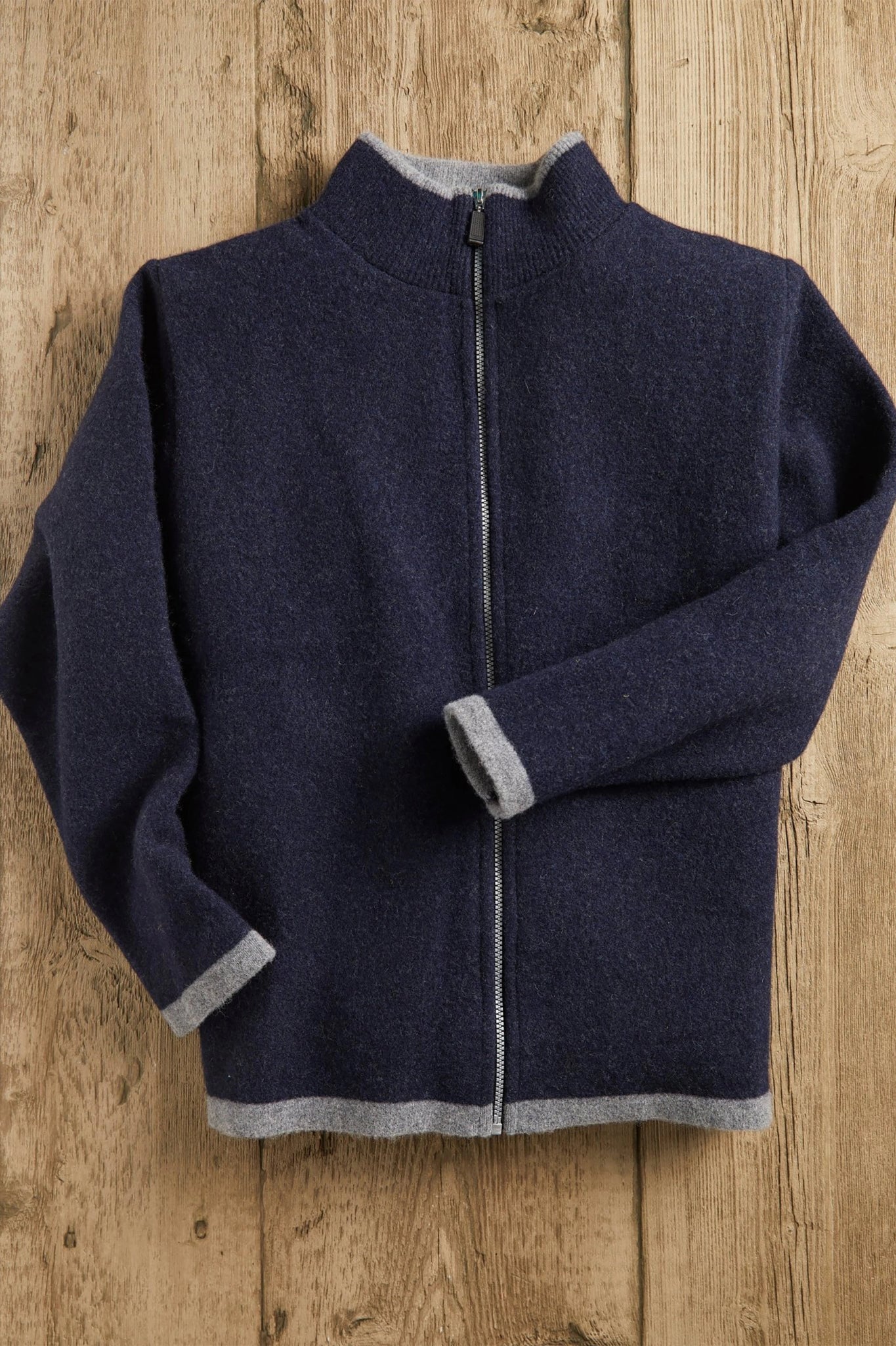 Men's Scottish Borders Felted Wool Cardigan in Navy with zipper fully closed laying on a wood background - L'Atelier Global