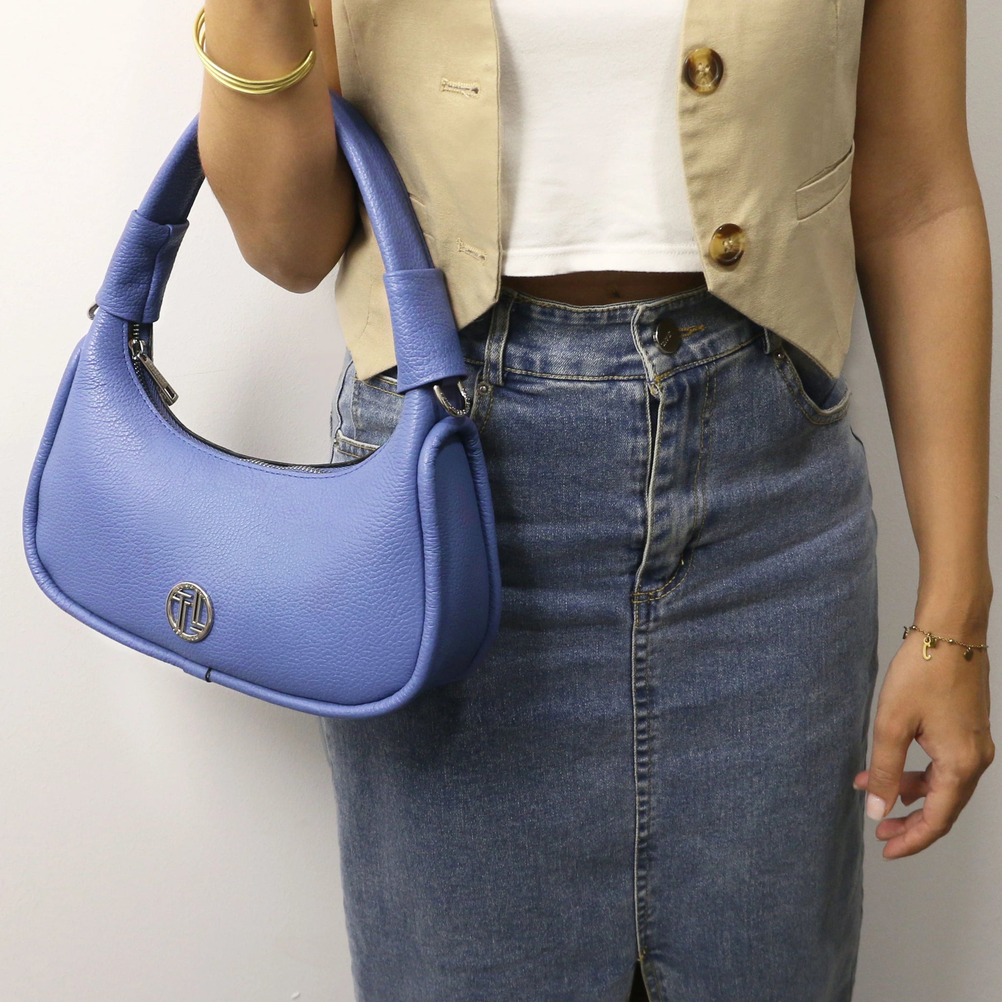Person holding a blue handbag with a visible brand logo against a neutral background