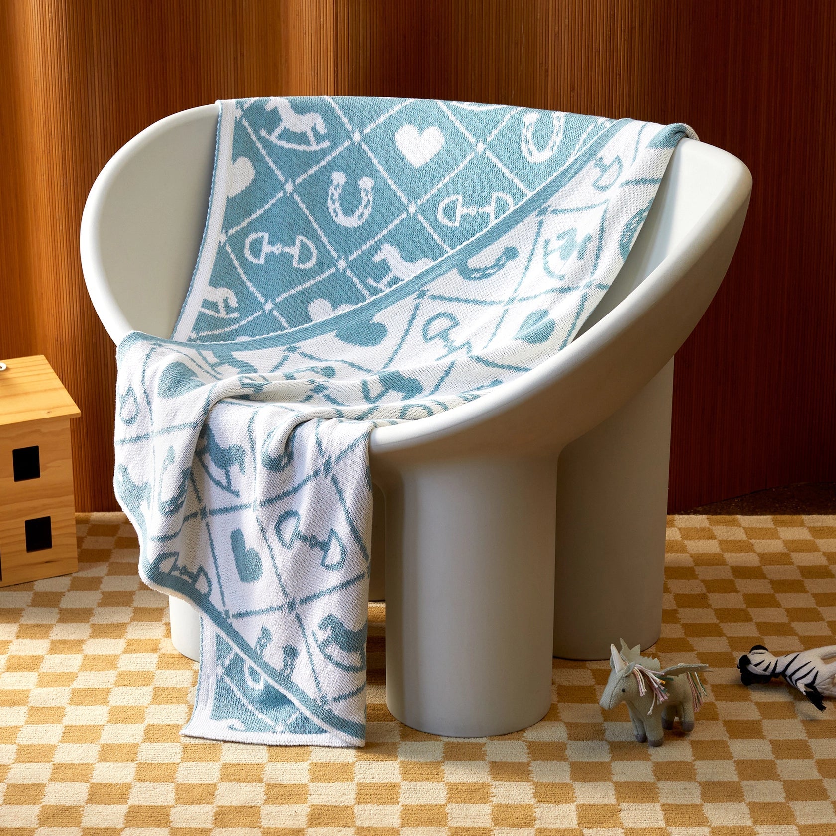 Pony Dreams Reversible Throw in Blue styled on a white child's chair showing both sides.