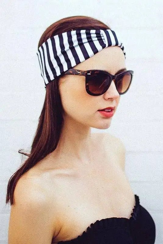 Woman wearing a black and white striped headband and sunglasses against a white background