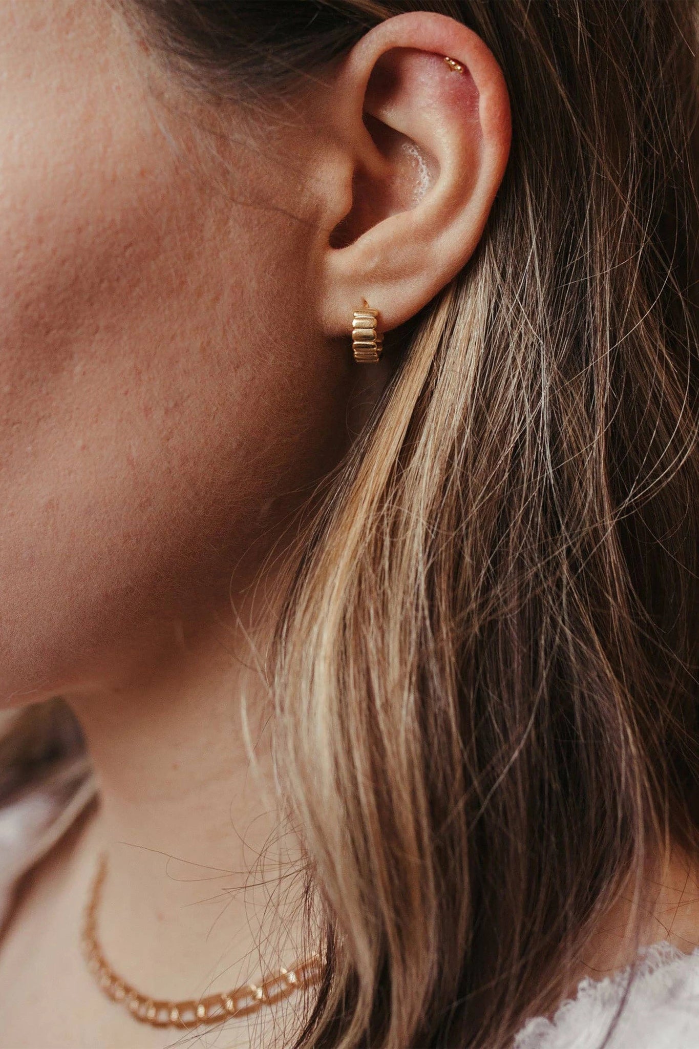 Ribbed Thick Gold Vermeil Hoop Earrings on a woman's left ear