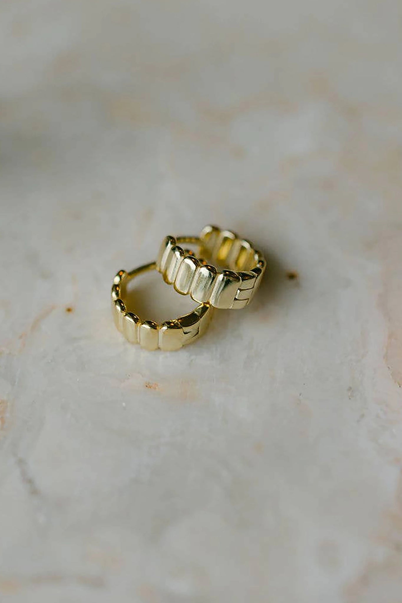 Ribbed Thick Gold Vermeil Hoop Earrings on a marble table