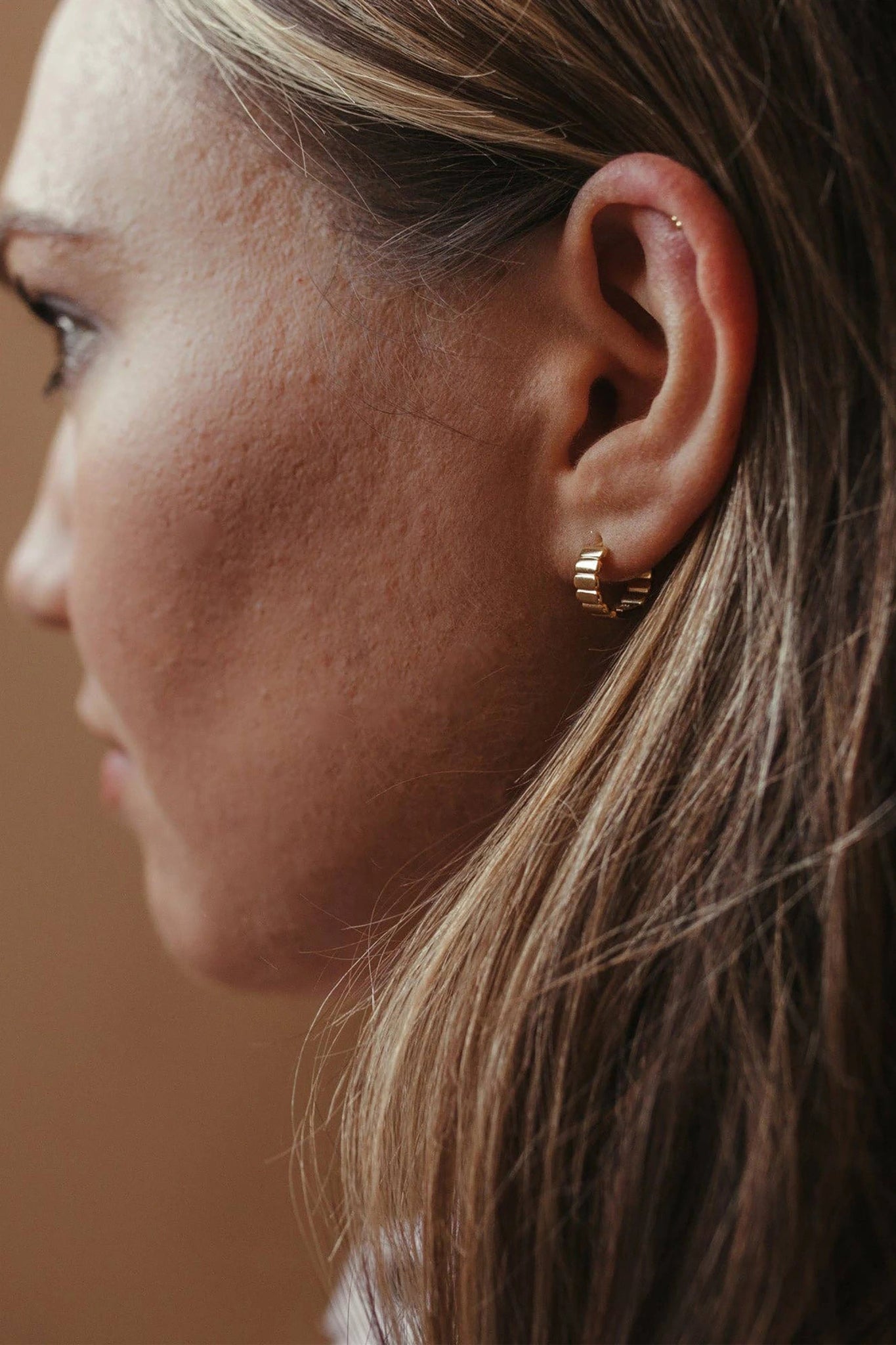 Ribbed Thick Gold Vermeil Hoop Earrings on a woman's left ear