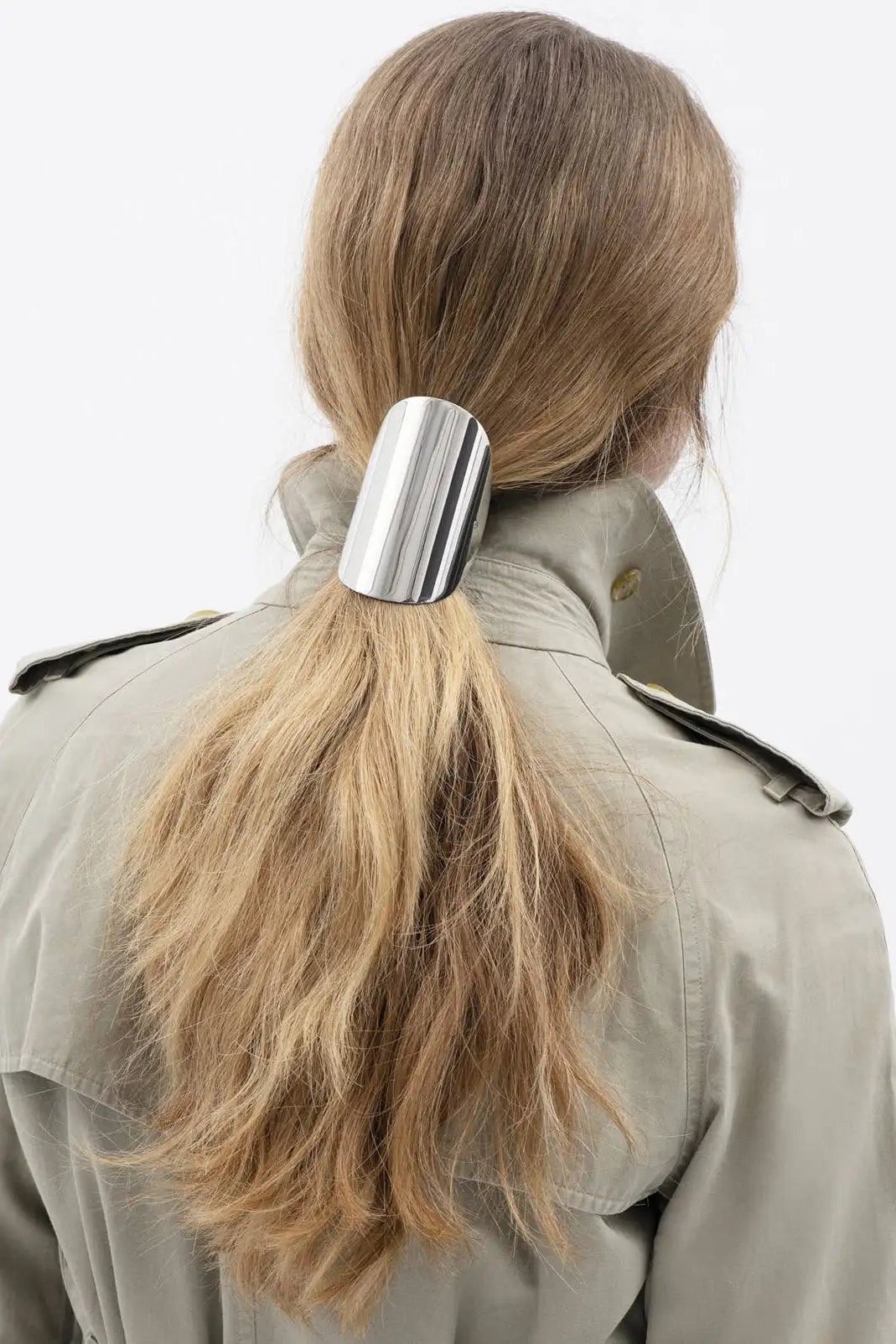 Woman with blonde long hair wearing the Sculpted Arc Barrette in her ponytail against a white background