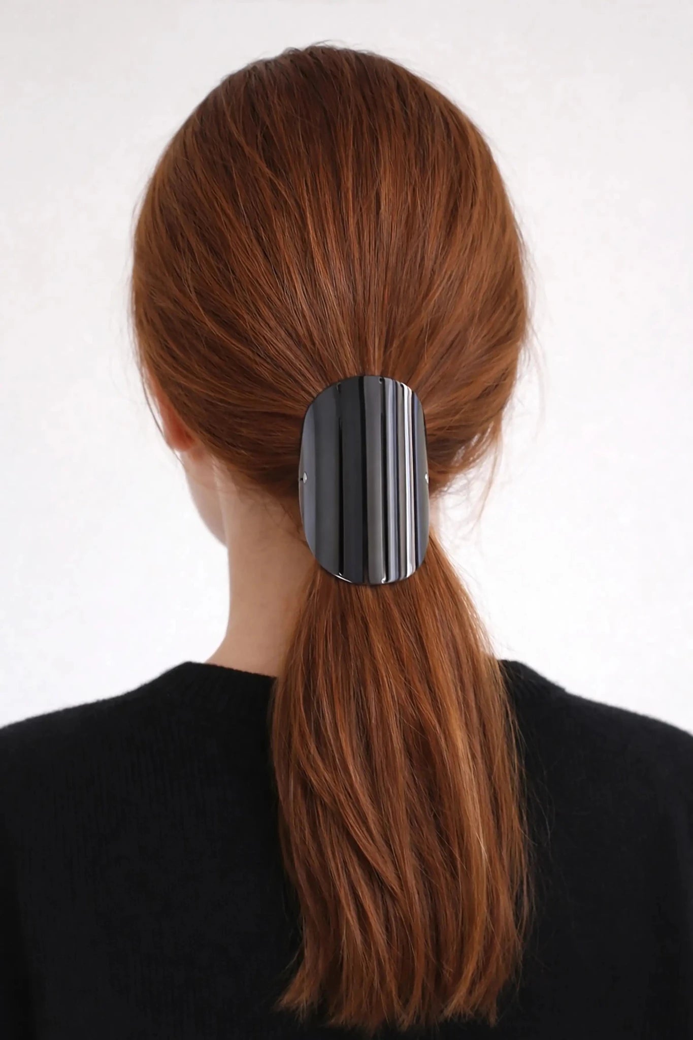 Woman with red long hair wearing the Sculpted Arc Barrette in her ponytail against a white background