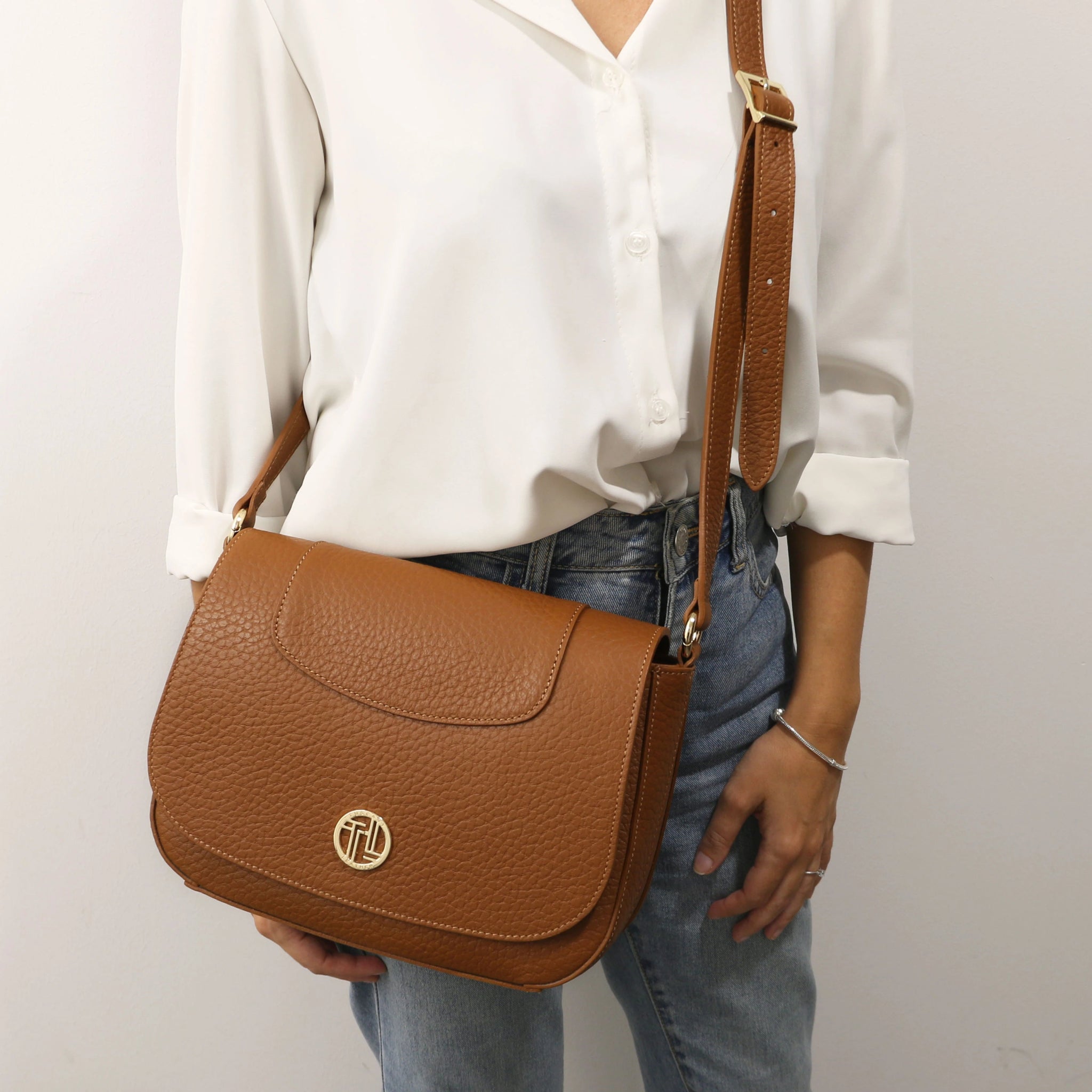 A woman is wearing the Sella Italian Leather Shoulder Bag in cognac as a crossbody