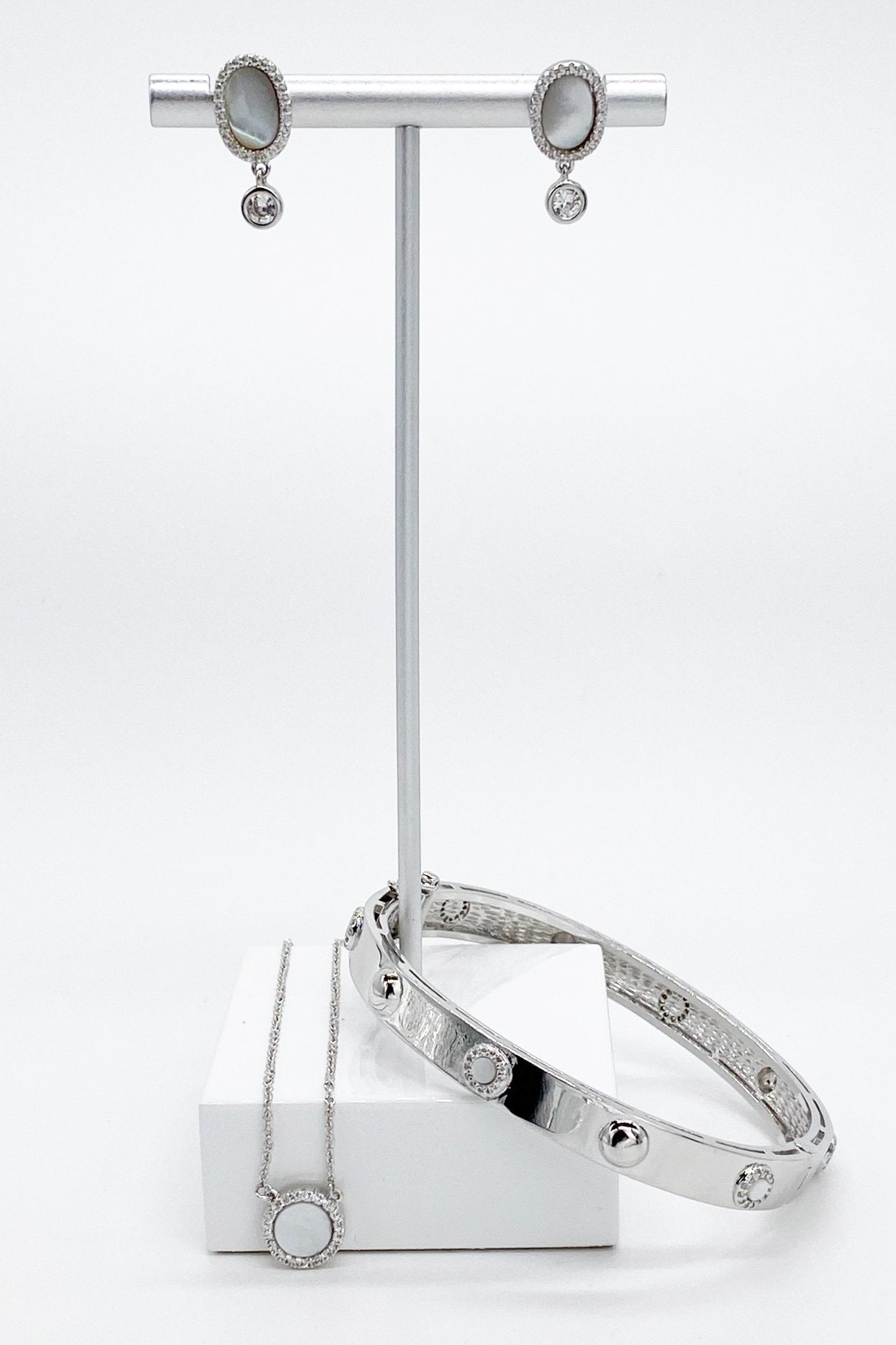 Silver Mother of Pearl Tier Drop Earrings, necklace and bracelet styled on a silver jewelry stand with a marble base.