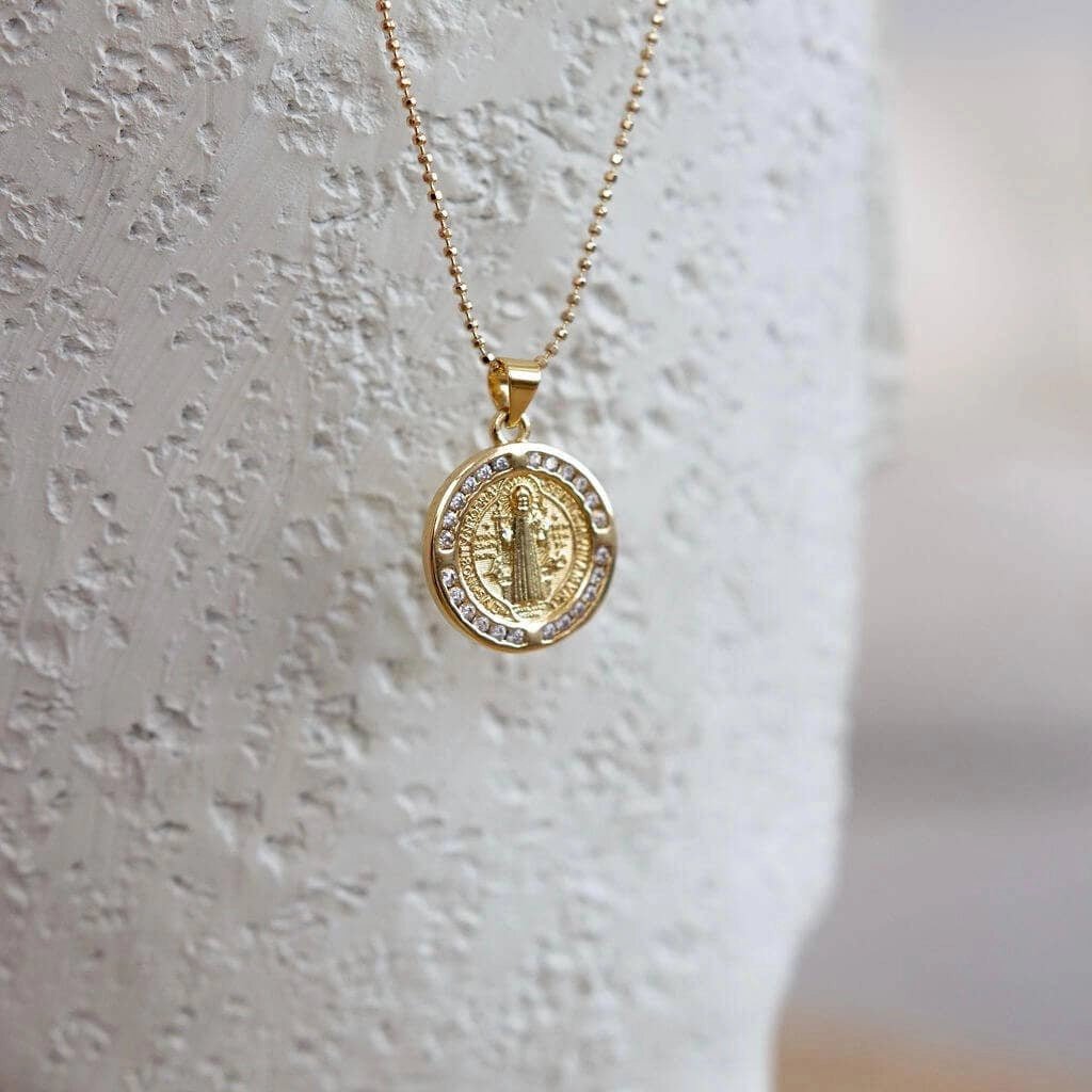 St. Benedict Coin Pendant Ball Chain in front of a ivory wall