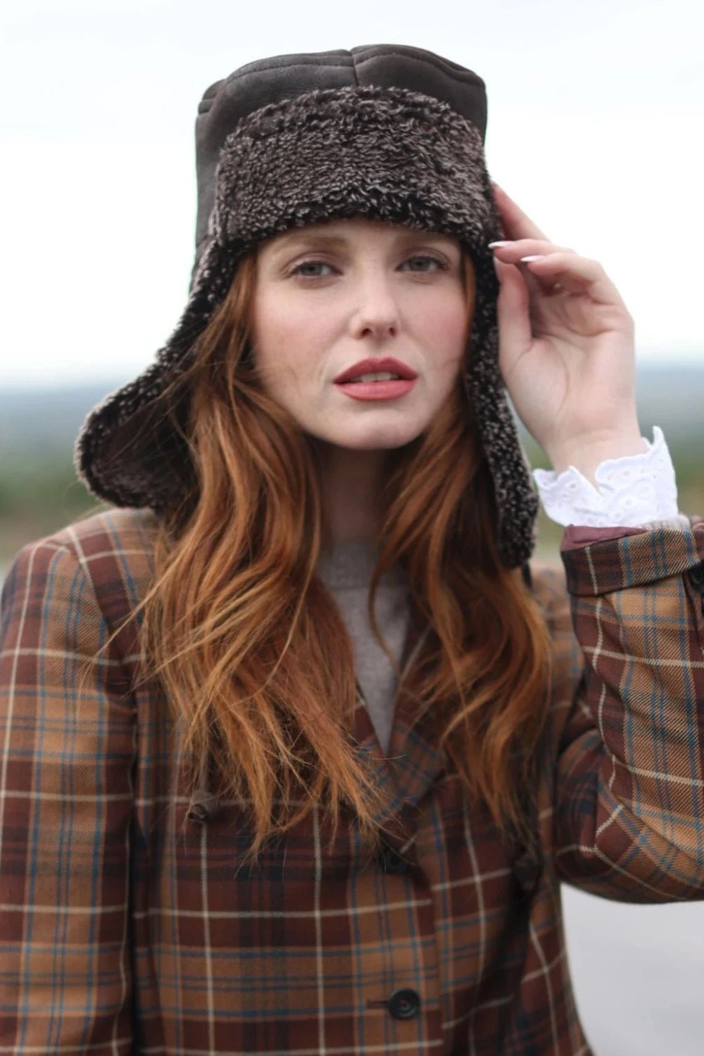 Tie Trapper Sheepskin Ear Flap Hat in Dark Brown on a female model, front view ear flaps down