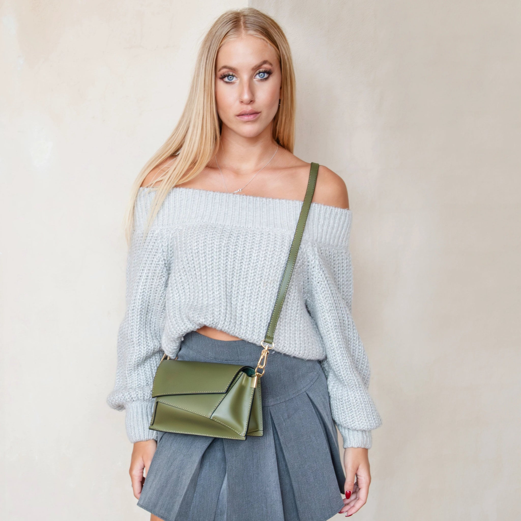 Woman is wearing Leather Asymmetrical Bag in forest green as a crossbody