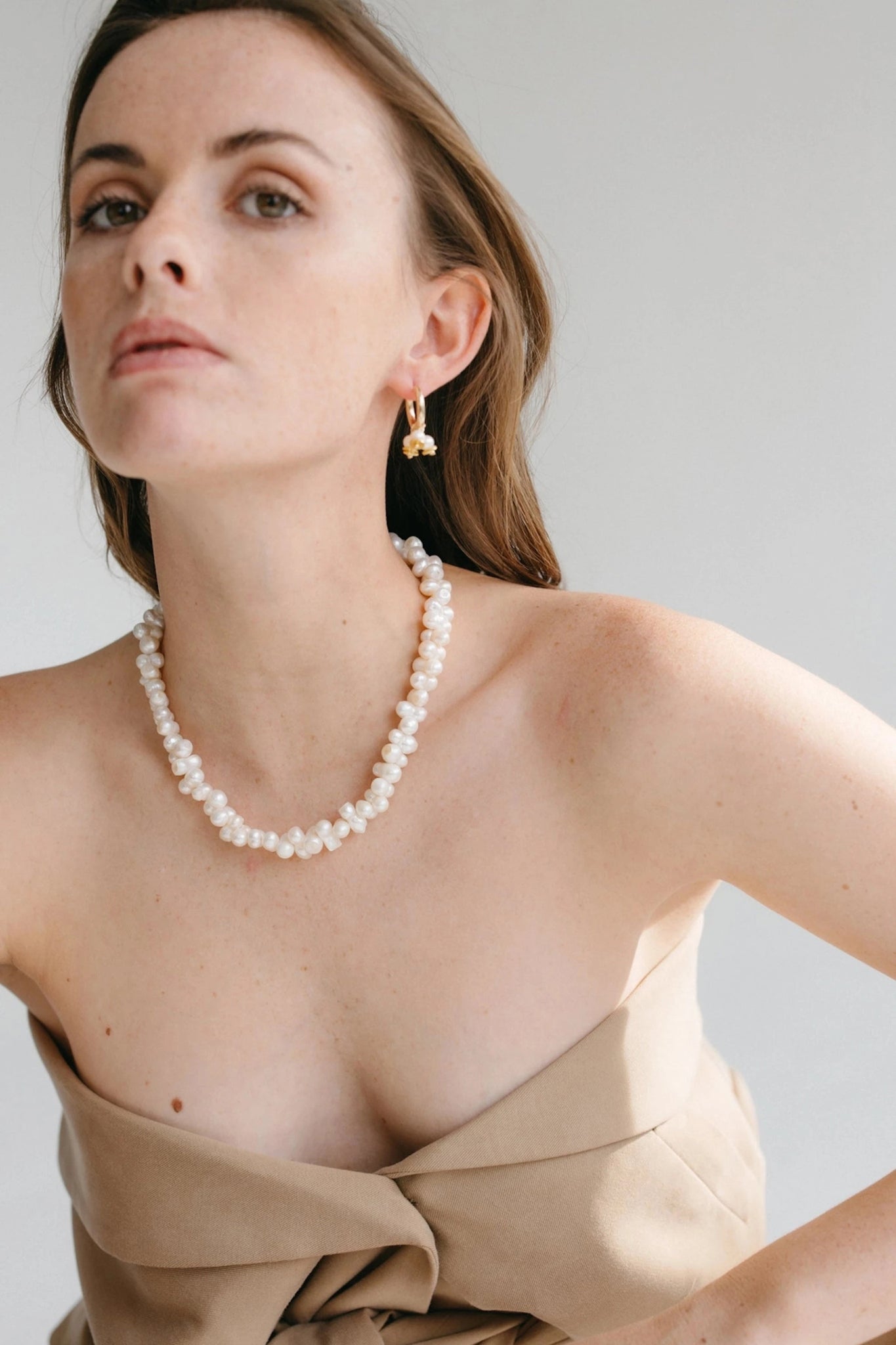 A model wearing the Valence Cultured Pearl necklace on a strapless khaki dress