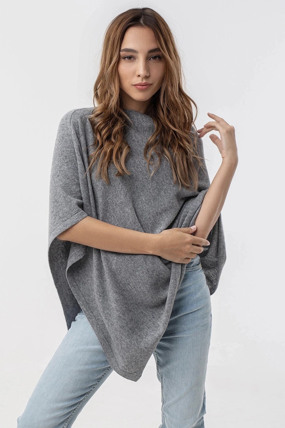 Siena Soft Cashmere Poncho in gray on a model with light brown wavy hair wearing light blue jeans - L'Atelier Global