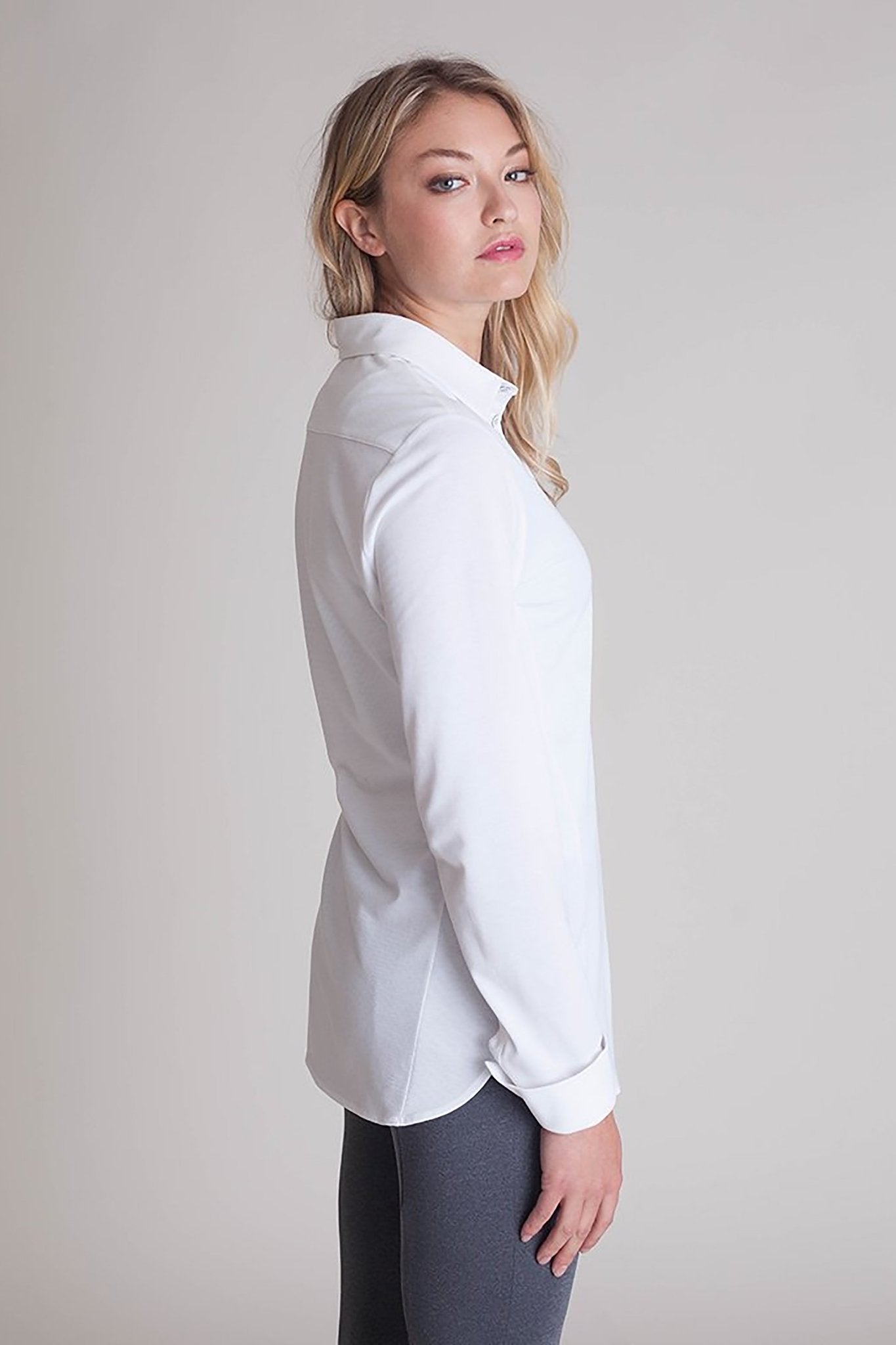 Side view of a female model wearing black pants and the All Day Comfort White Shirt - L'Atelier Global