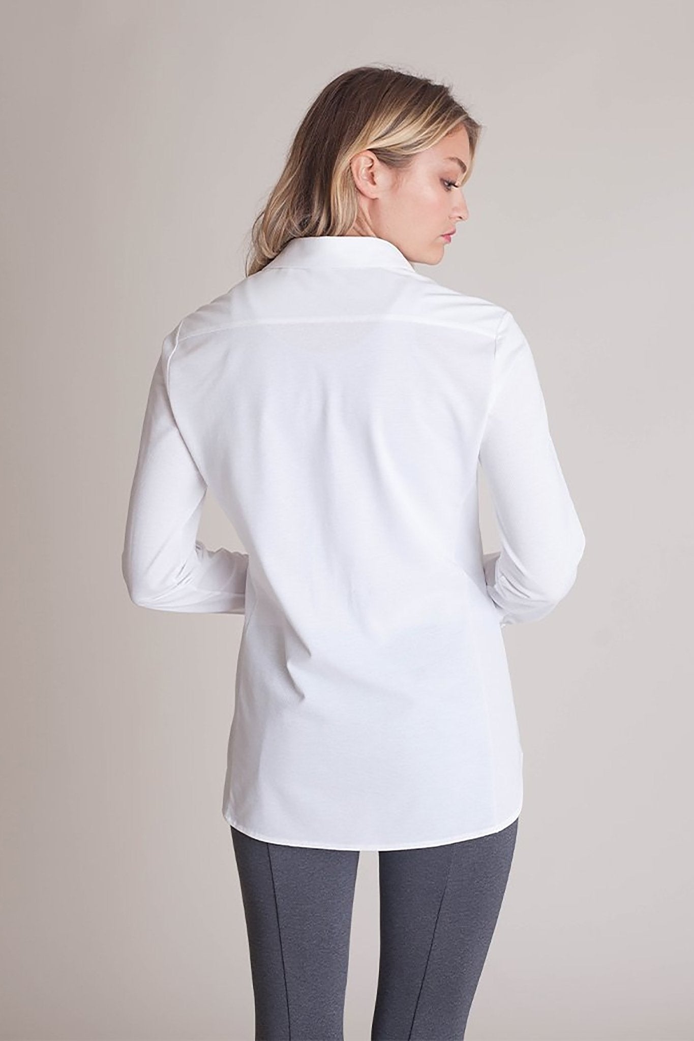 Back view of a female model wearing black pants and the All Day Comfort White Shirt - L'Atelier Global