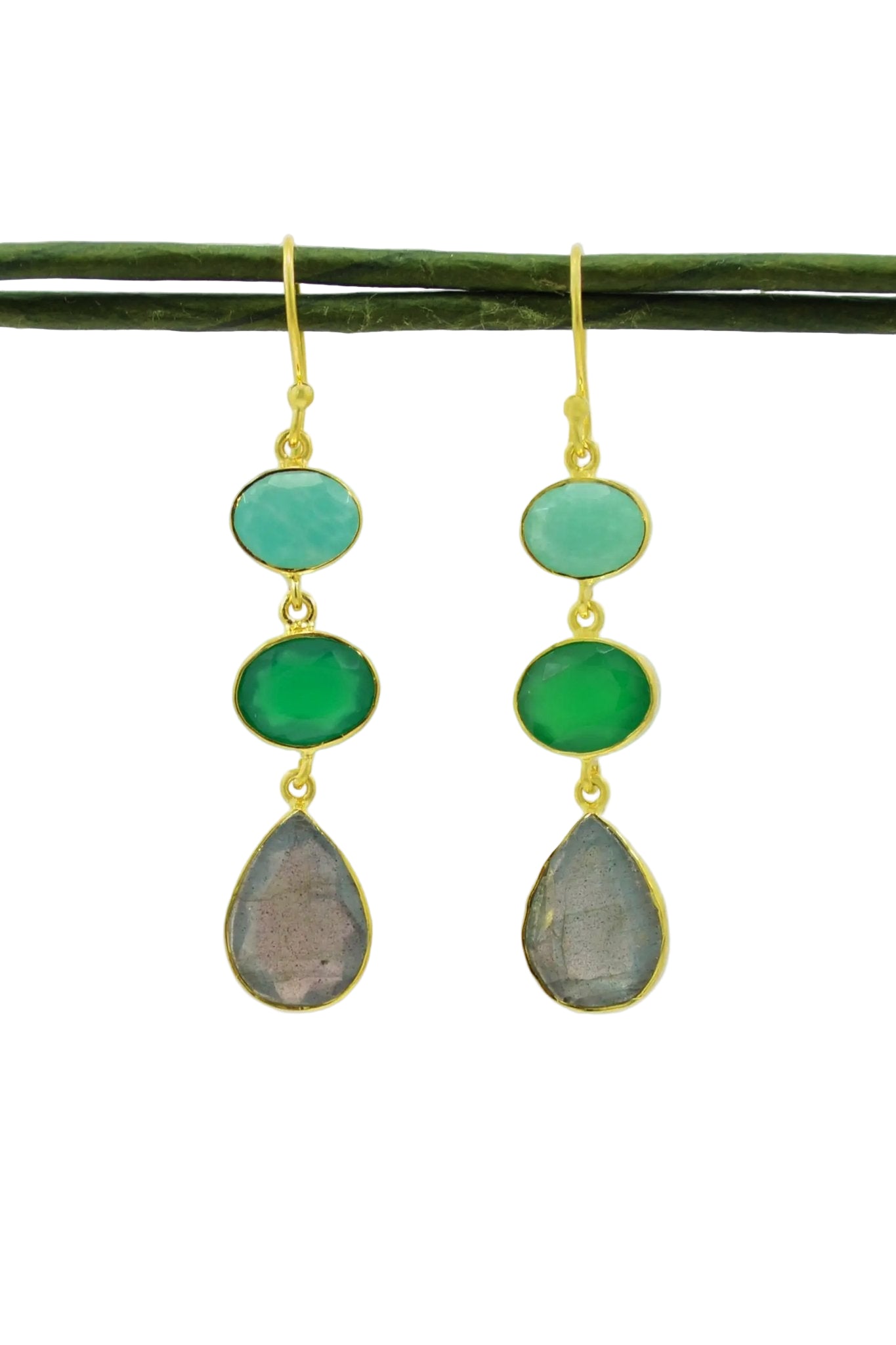 Amazonite, Green Onyx & Labradorite Earrings is hanging from a green branch in front of a light gray background