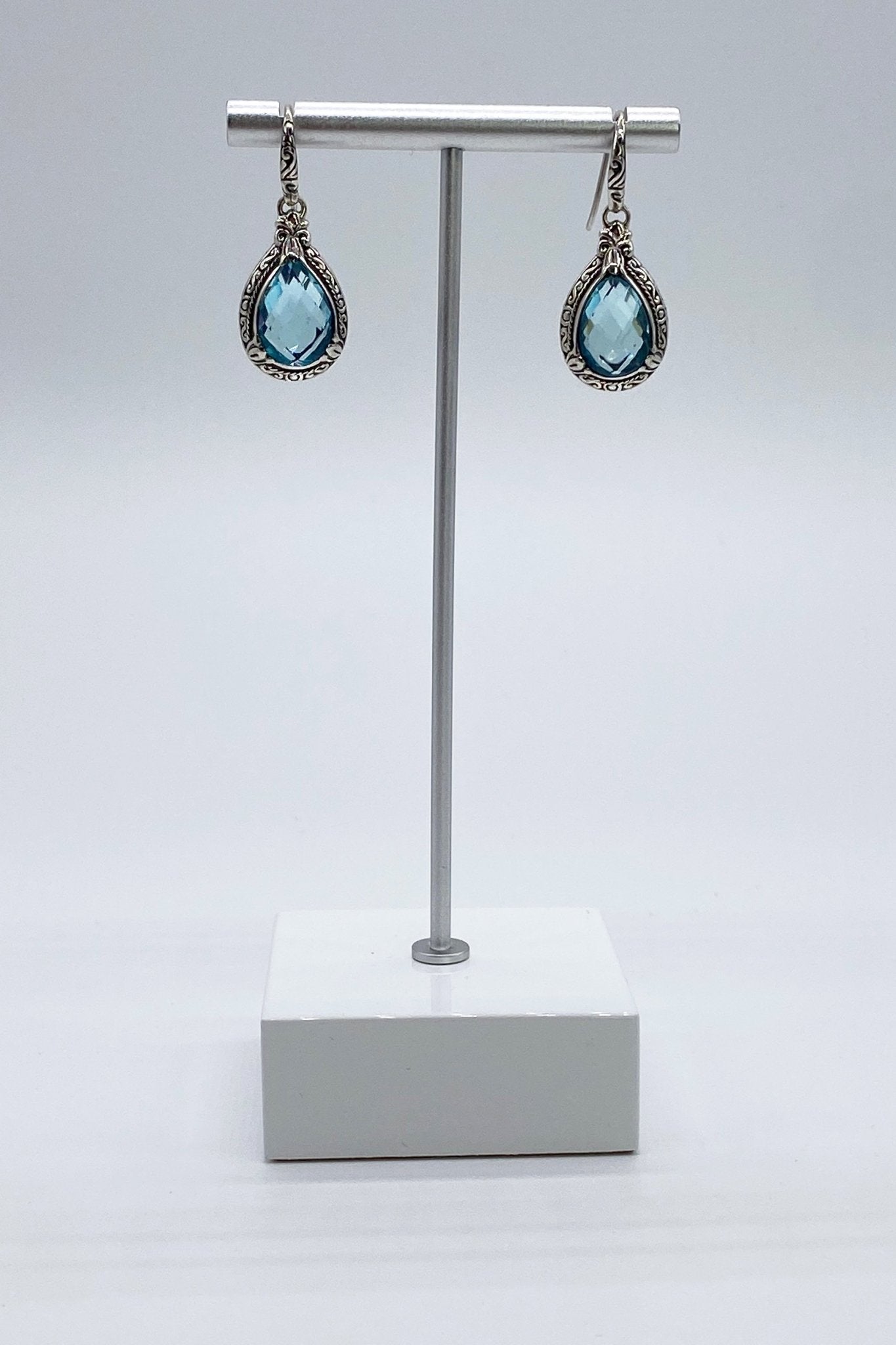 Balinese Sterling Silver Earrings in Blue Topaz on a white and silver jewelry stand