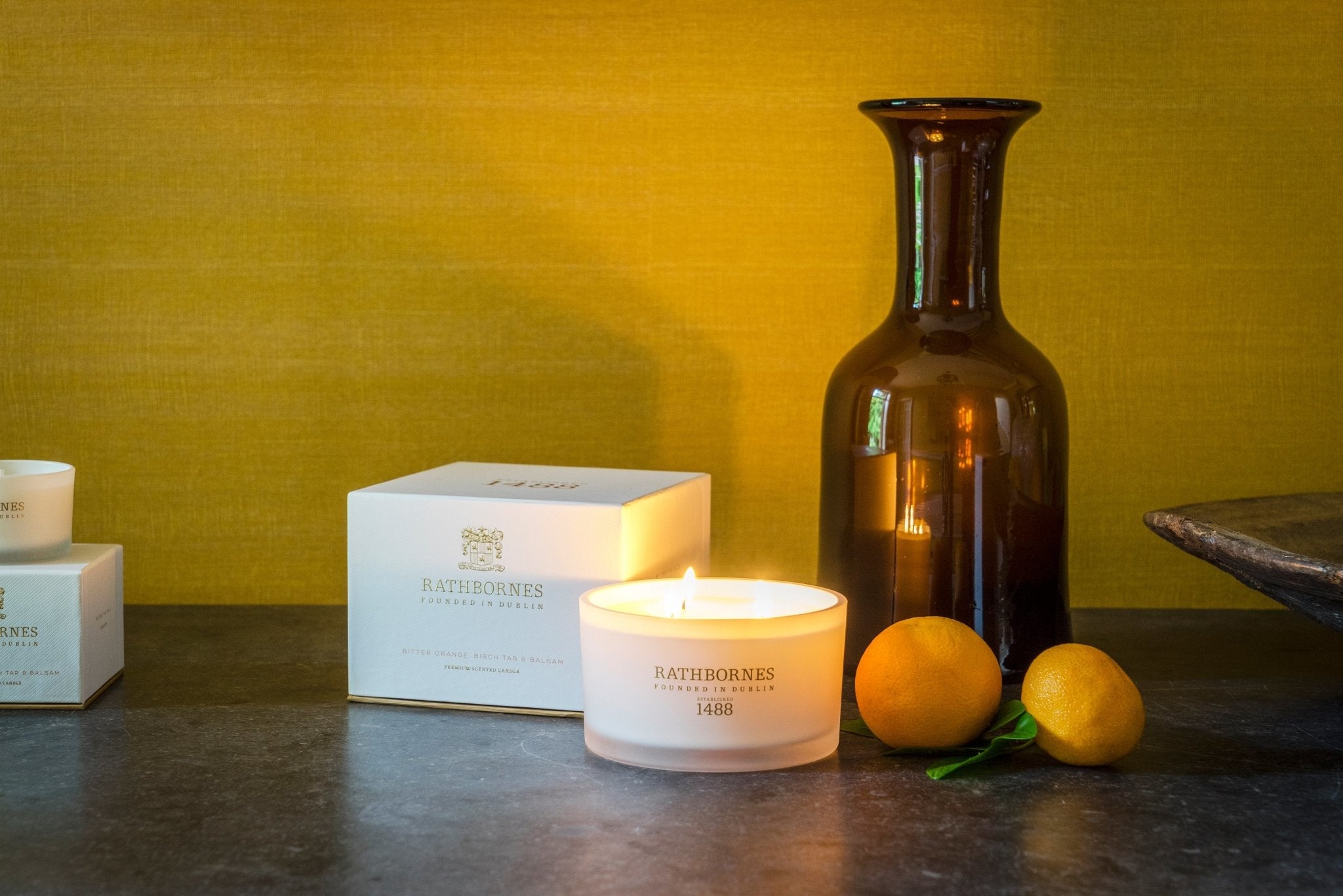 Bitter Orange, Birch Tar and Balsam Luxury Beeswax Candle displayed in a living room on a wooden table - L'Atelier Global