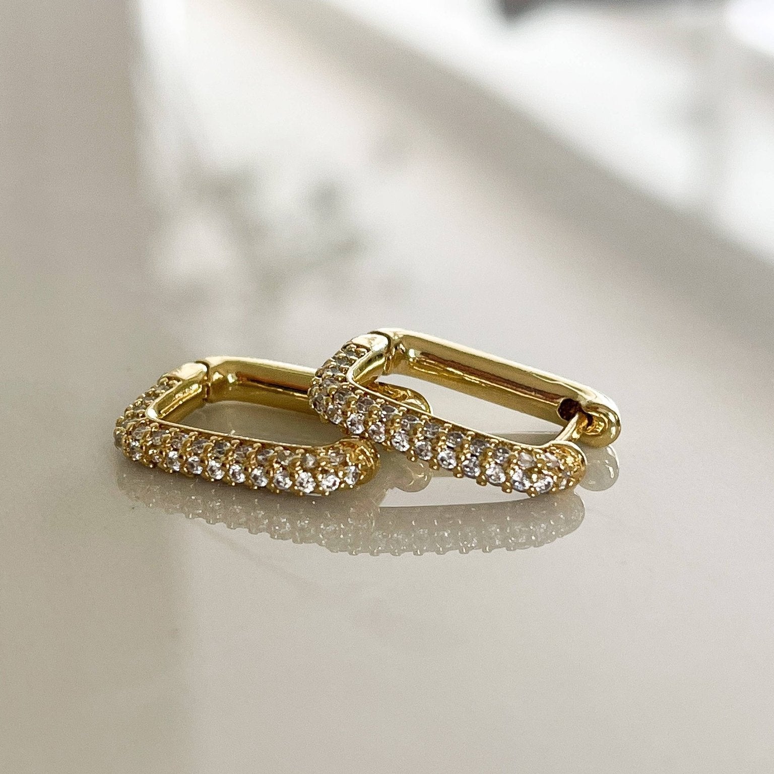 Boca Cubic Zirconia Pavé Gold Earrings on a glass table showing a reflection