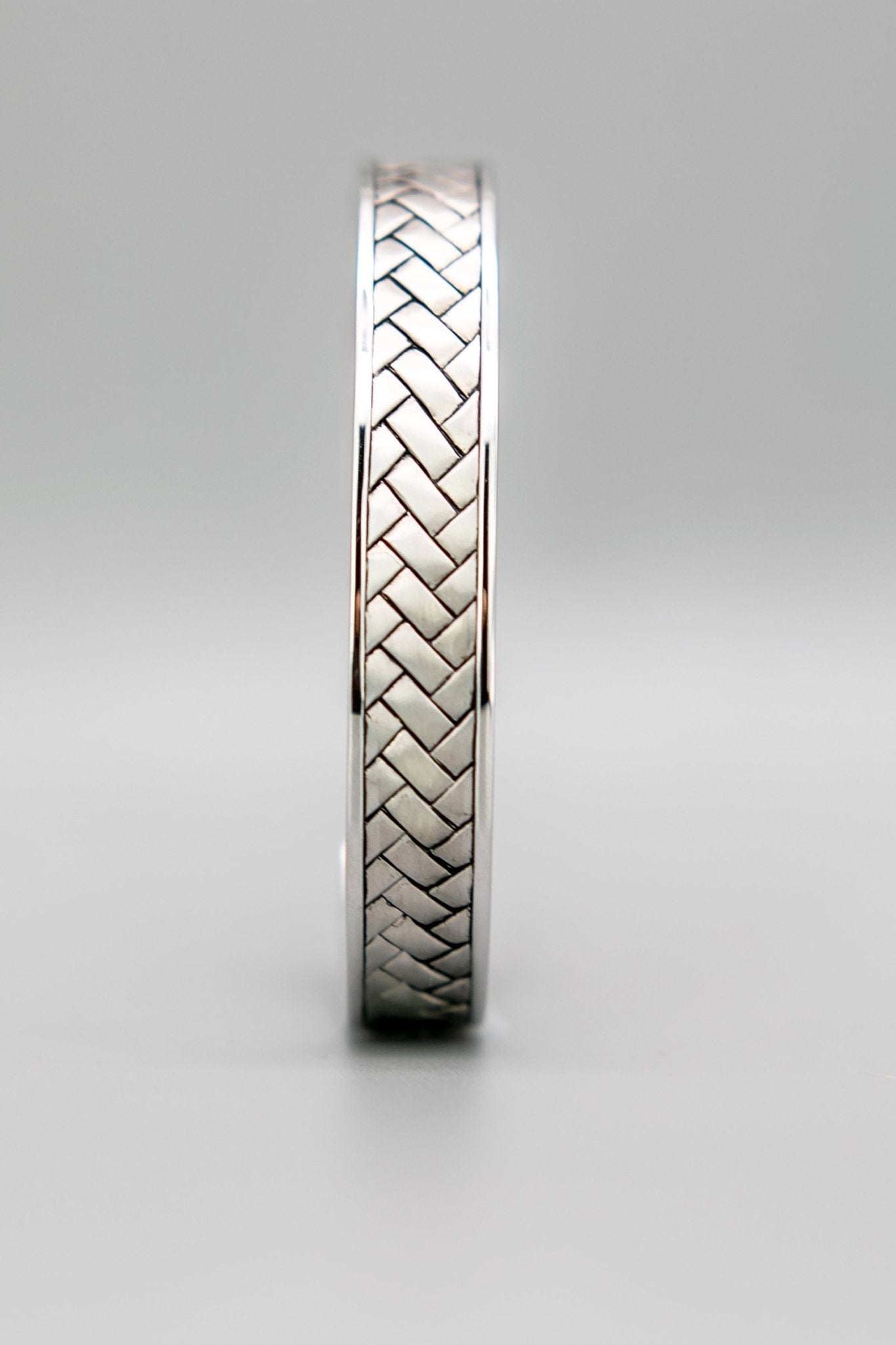 Broken Twill Weave Cuff Silver Bangle front View on a grayish background-