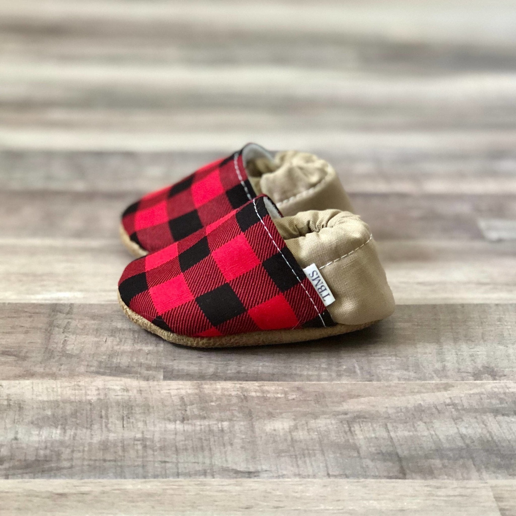 Side view Buffalo Plaid And Tan Moccasins on a soft ash hued wood table