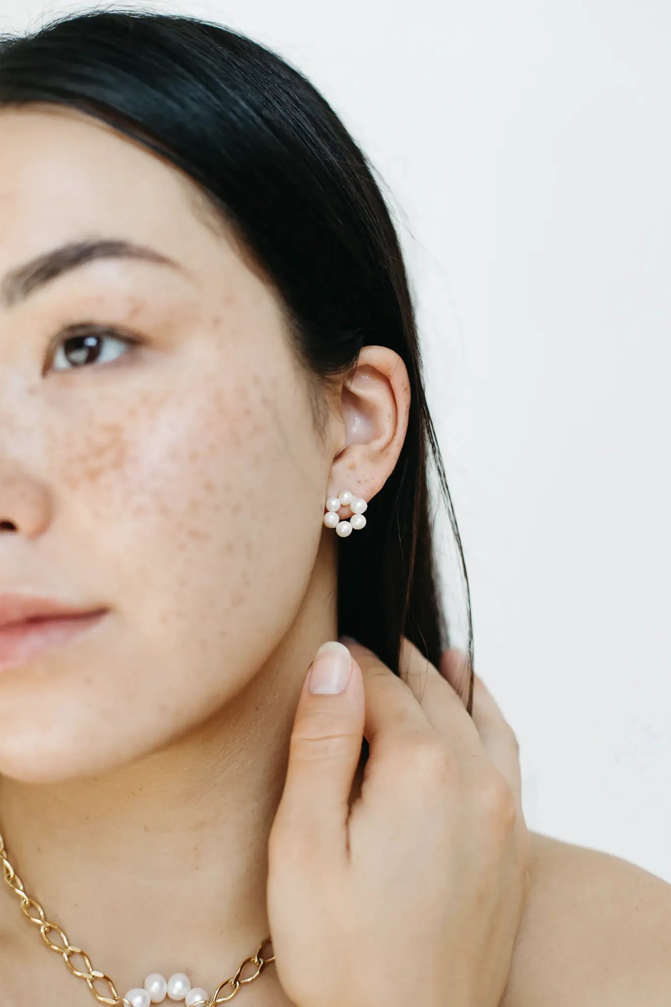 Charlotte Cultured Pearl Earrings on a model presenting her left ear. Six pearls form a petal.