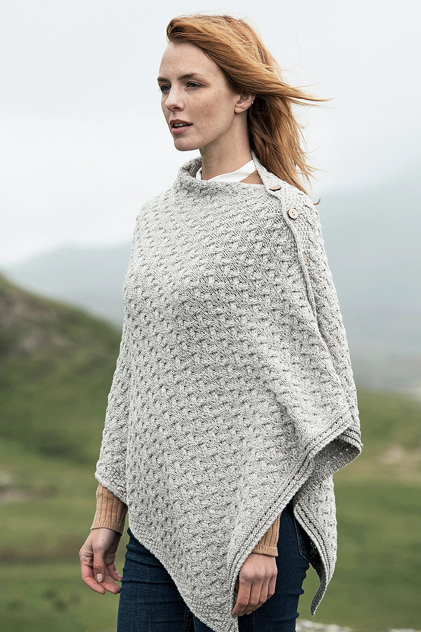 A female model wearing the Irish Clew Bay Supersoft Convertible Cape in oatmeal as a poncho