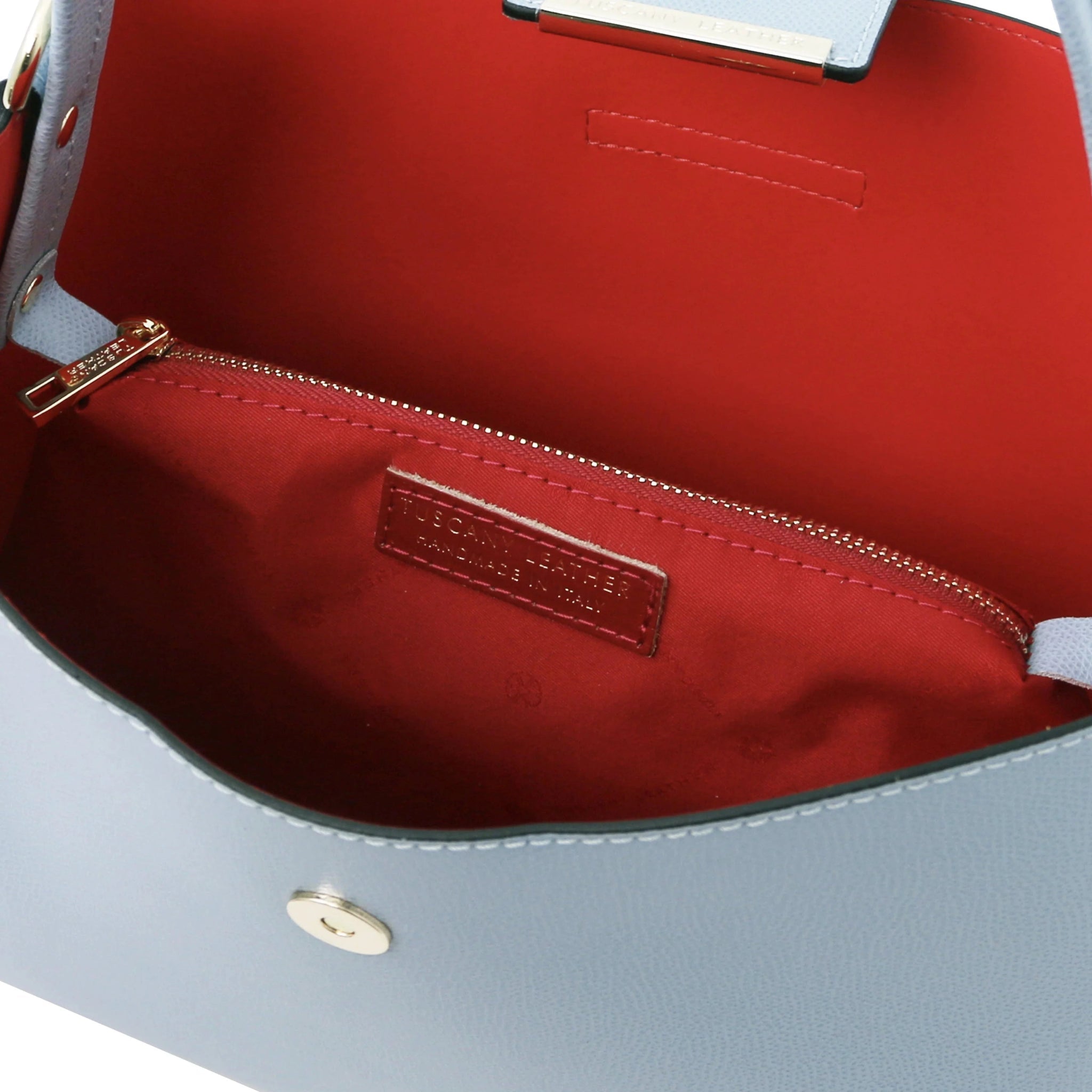Interior central zippered compartment and vibrant red lining view of the Clio r Secchiello Bag in Light Blue