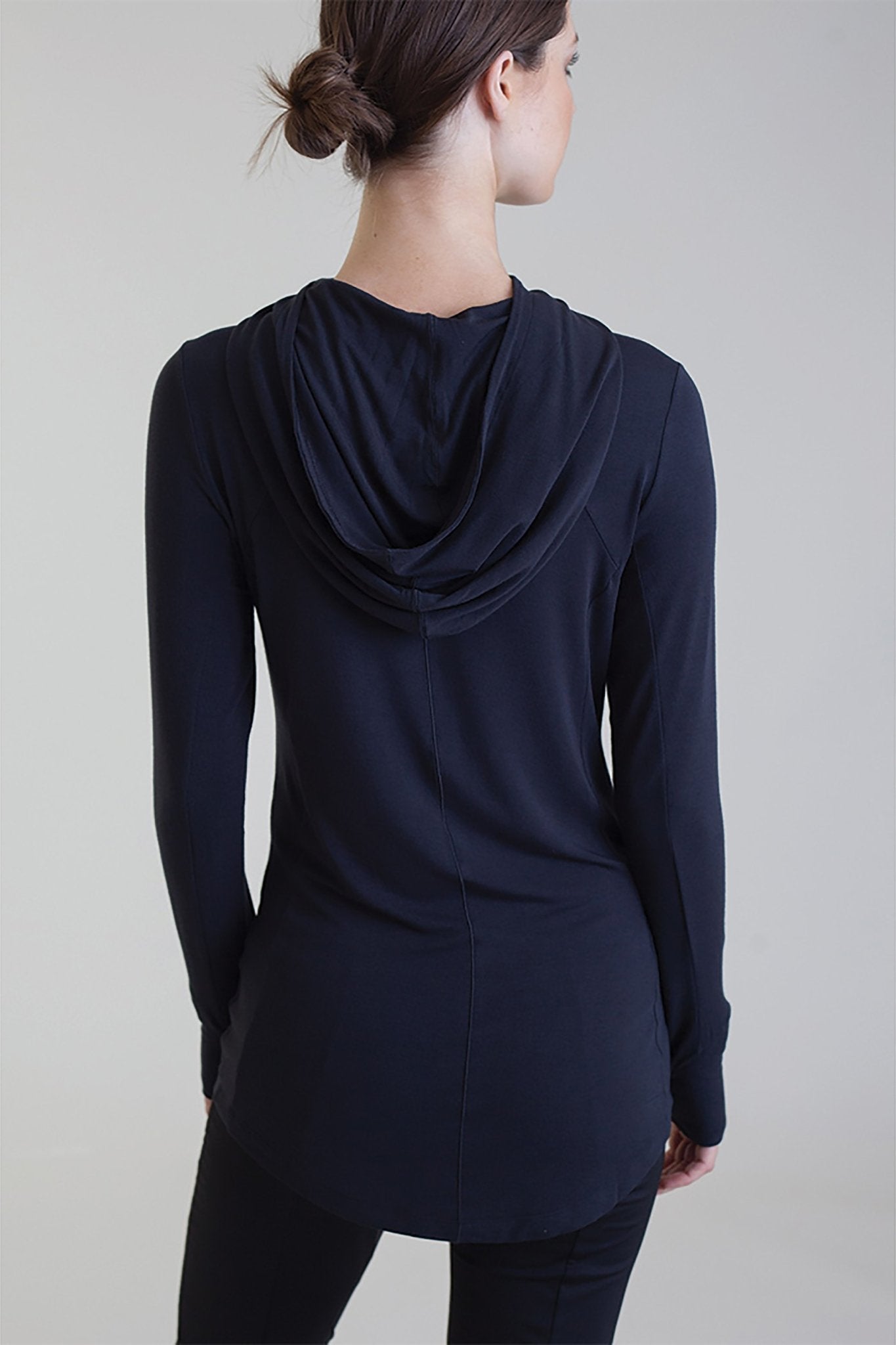 Back view of a female model wearing black pants and the Comfort Collagen Hoodie - L'Atelier Global