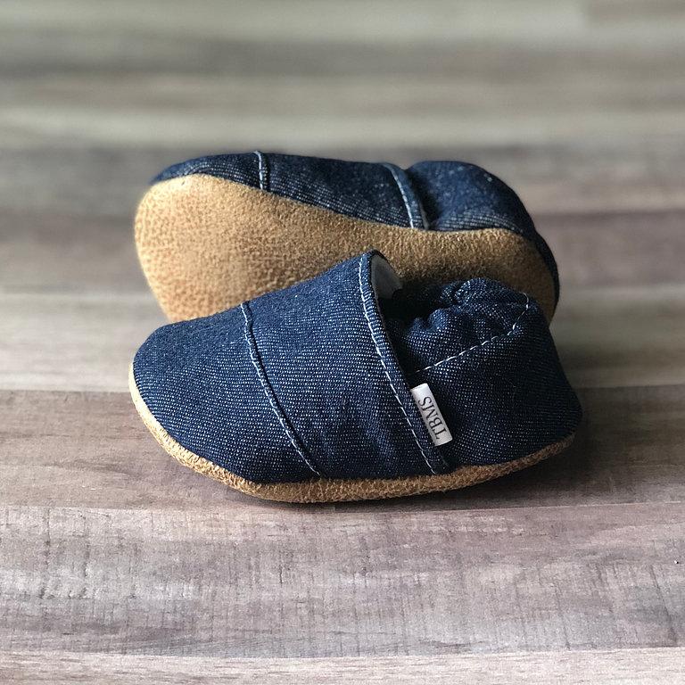 Baby Moccasins in Denim photographed on a wooden floor showing the bottom of the moccasin