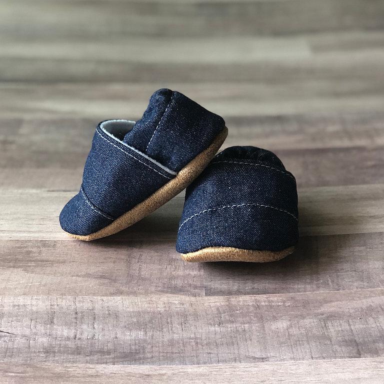 Baby Moccasins in Denim photographed on a wooden floor