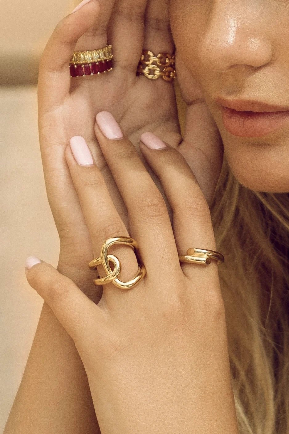 Downtown Golden Ring on a women's index finger layered with other gold rings