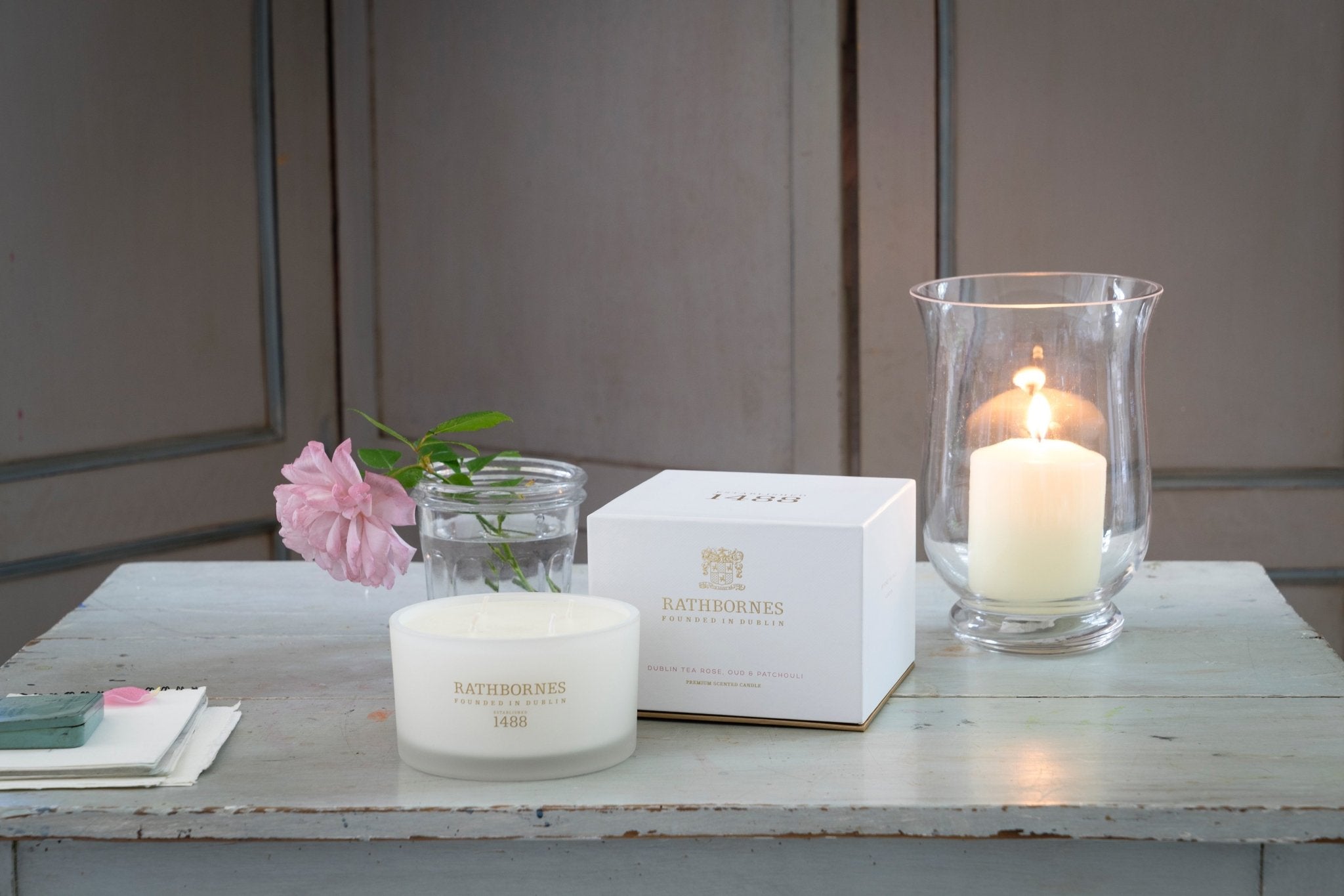 Dublin Tea Rose, Oud and Patchouli Scented Luxury Beeswax Candle shown on counter with a pink rose