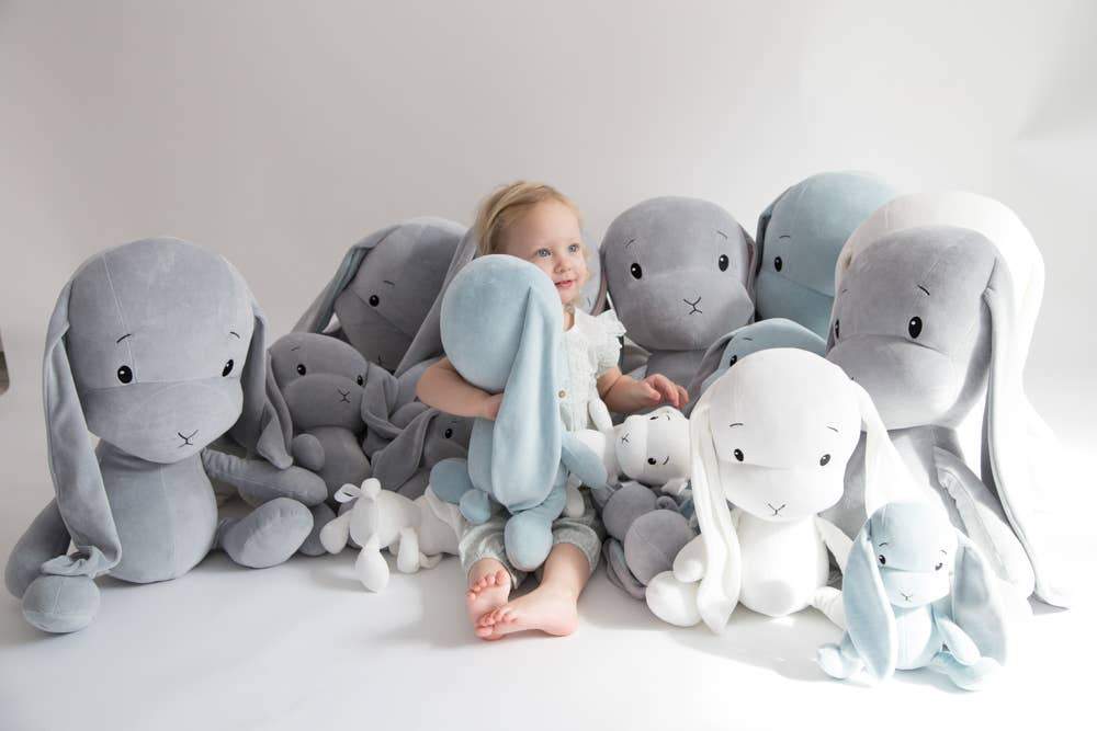 A group of different-sized Effik Gray Bunnies on a sofa with a young child - L'Atelier Global