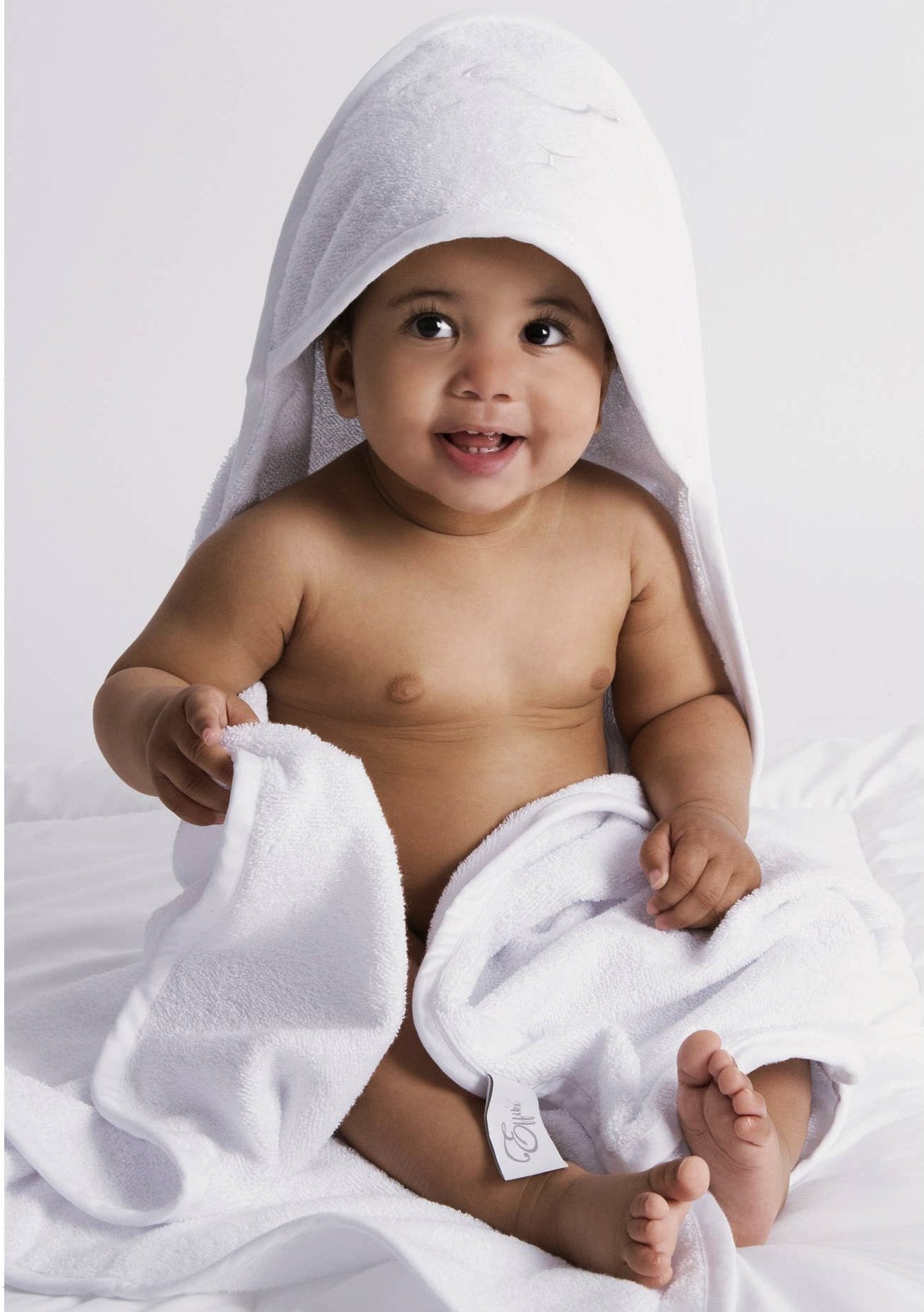 Embroidered Hooded Towel in White wrapped around a smiling baby - L'Atelier Global