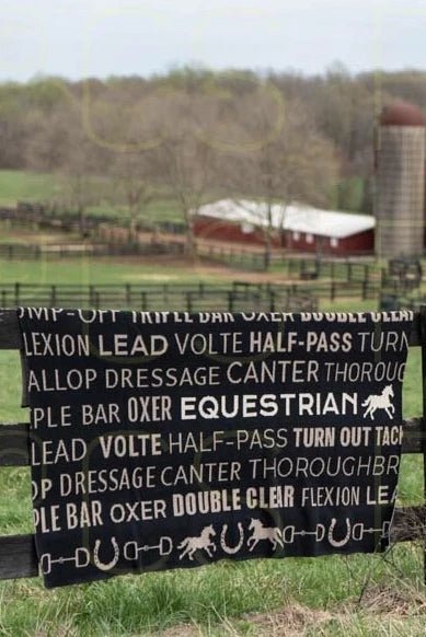 Equestrian Eco Text Throw is folded over a black paddock fence with a red barn in the background