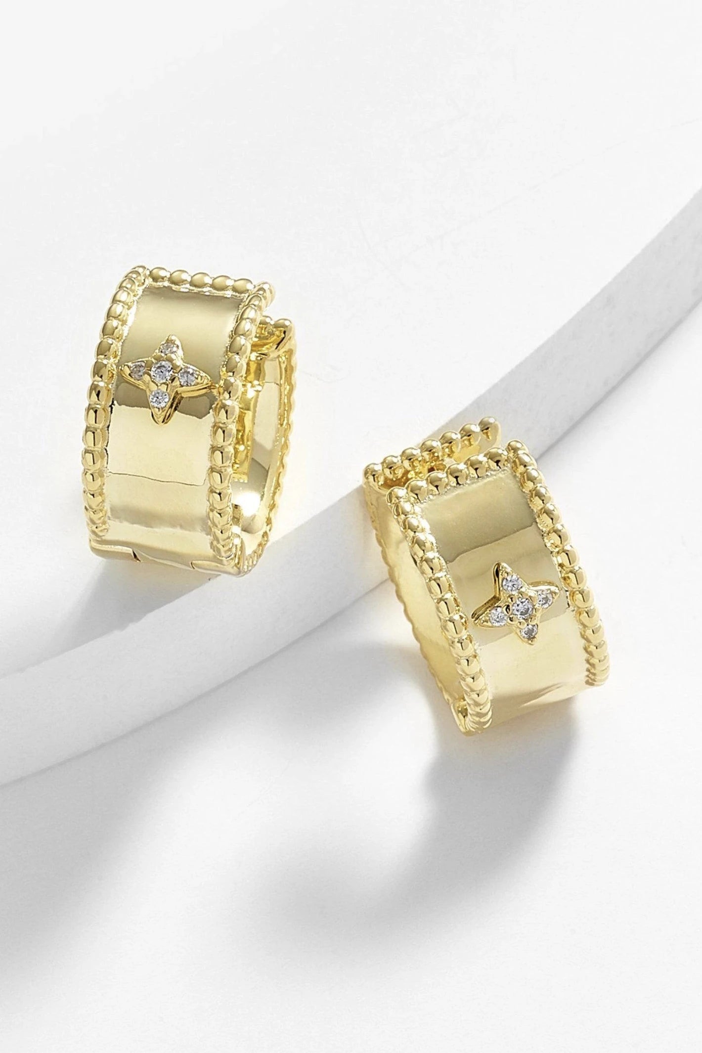 Firenze Cuff Star Earrings in gold on a white background. The vintage diamond star shape is seen in the front of the hoop.
