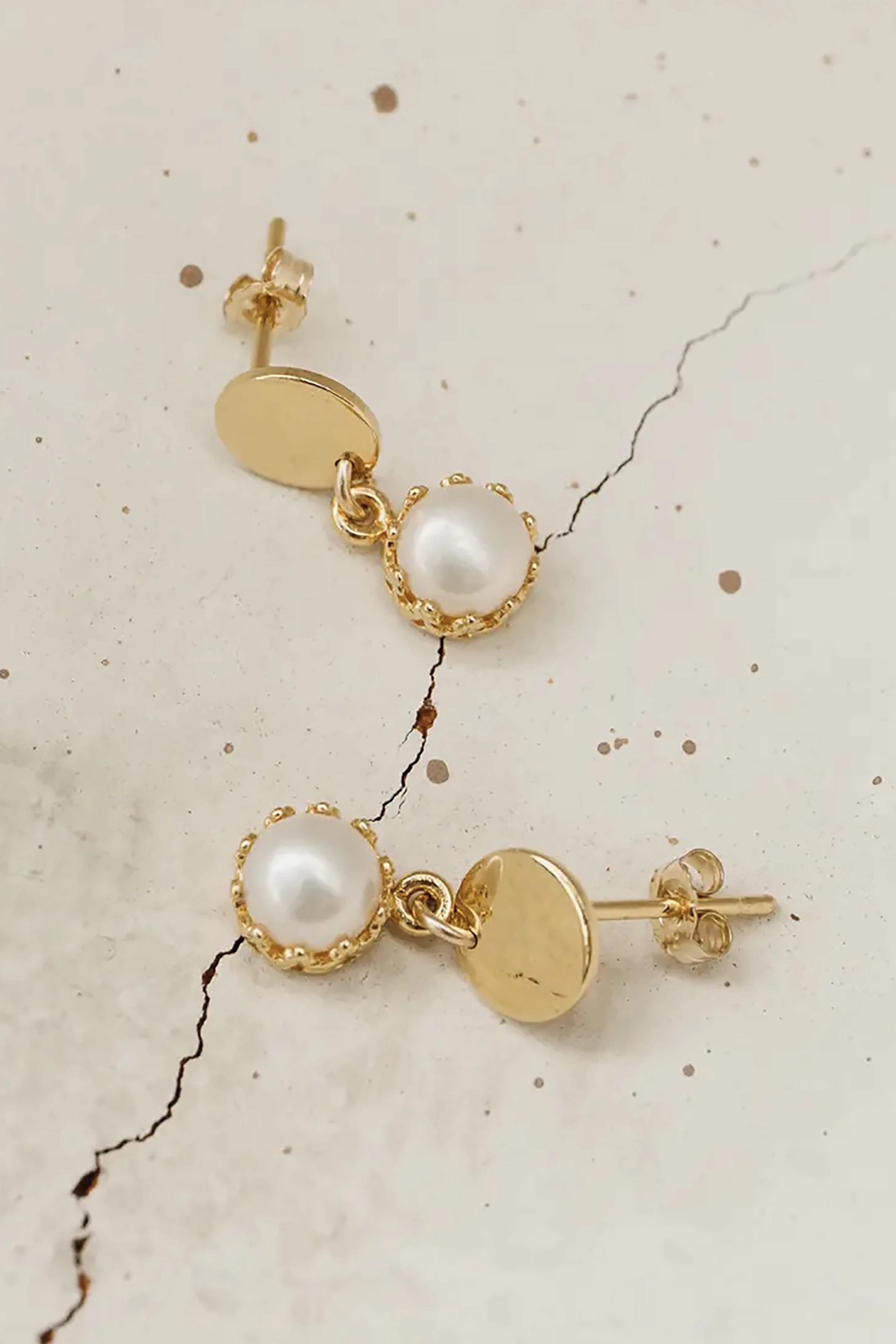Fontaine Freshwater Pearl Gold Earrings on a beige stone background