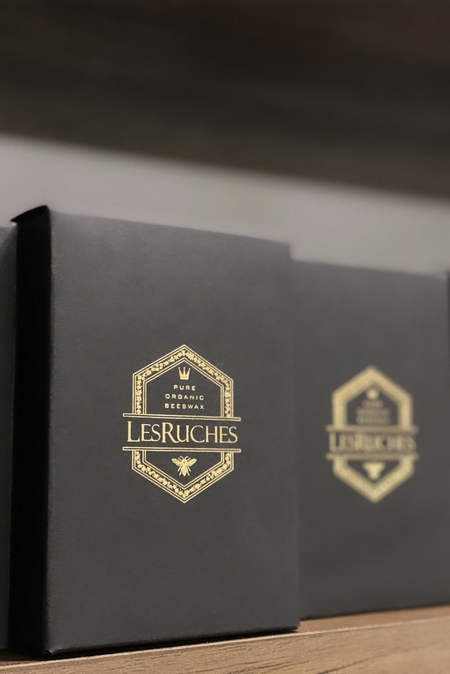 Les Ruches black candle boxes with gold branding on a shelf