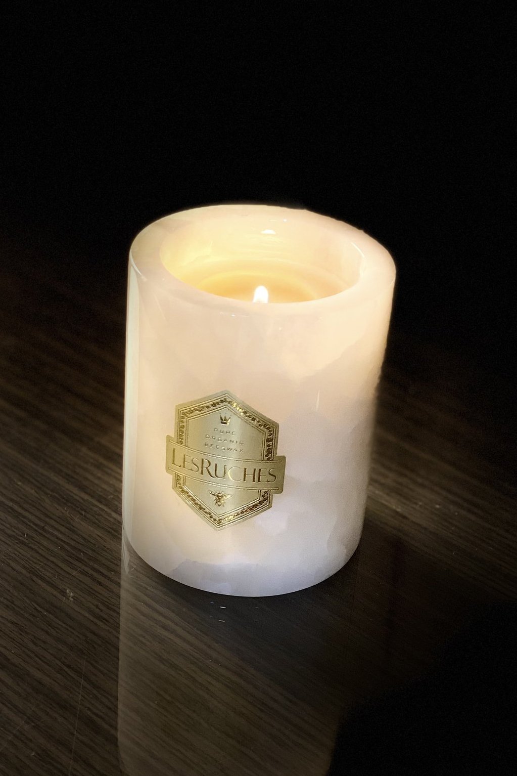 Gardenia Onyx Partfaite Beeswax Candle 8 oz on a wooden table in a dark room