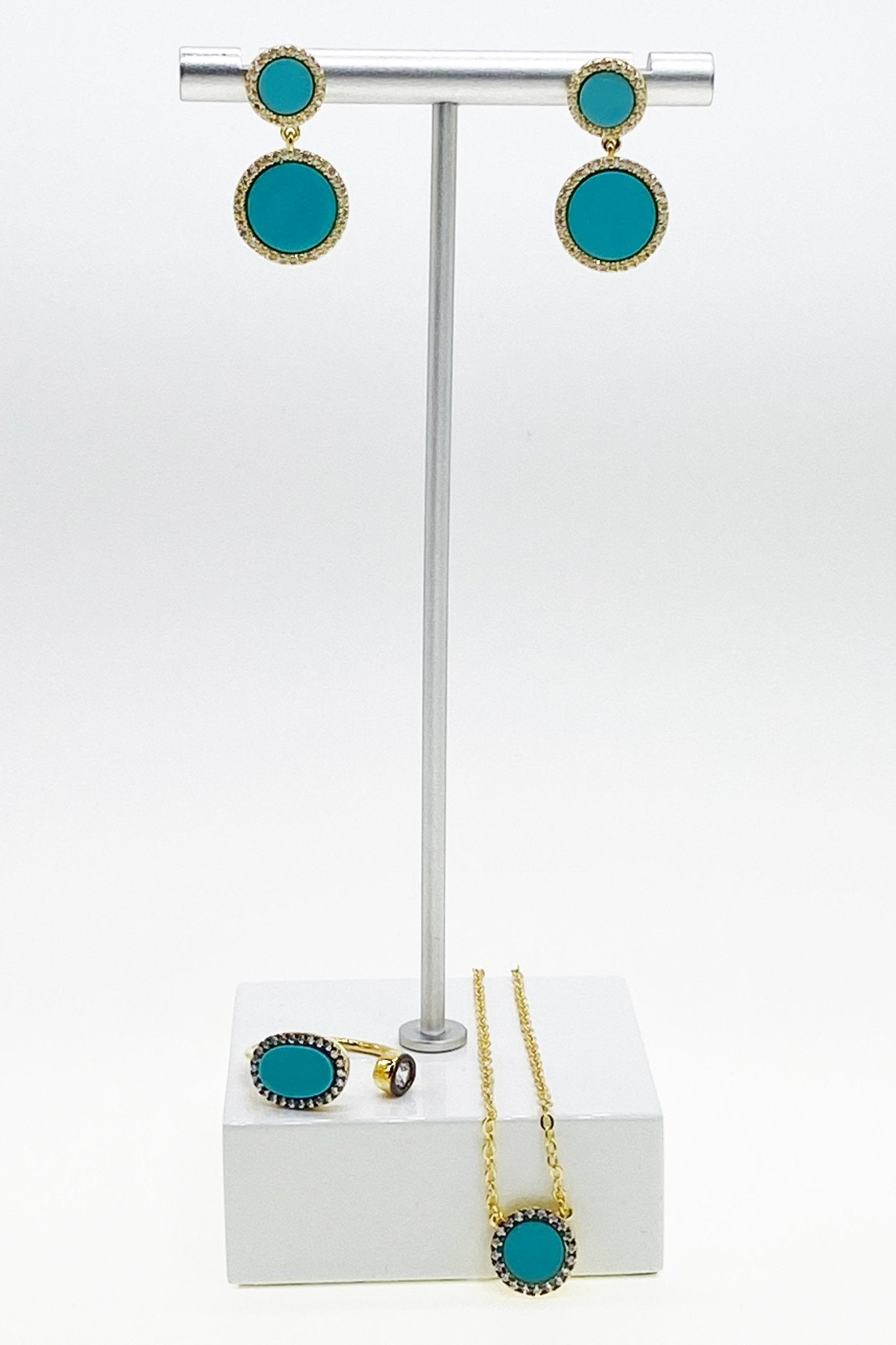 Gold and Turquoise Drop Earrings and necklace on silver jewelry stand with white marble base