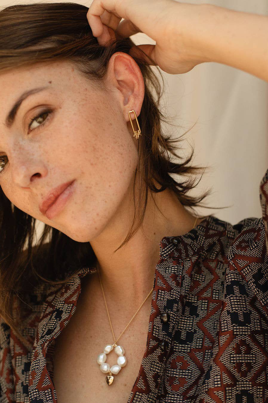 Gold Coast Dangle Earrings on model presenting the earring on her left ear. 3/4 of the earring lays below the ear.