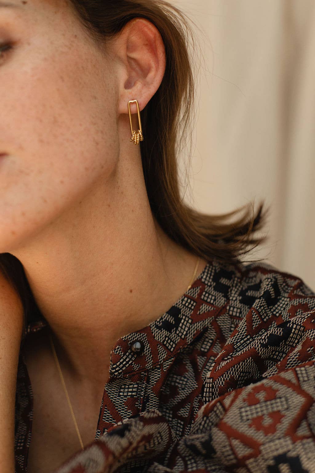 Gold Coast Dangle Earrings on model presenting the earring on her left ear. 3/4 of the earring lays below the ear.