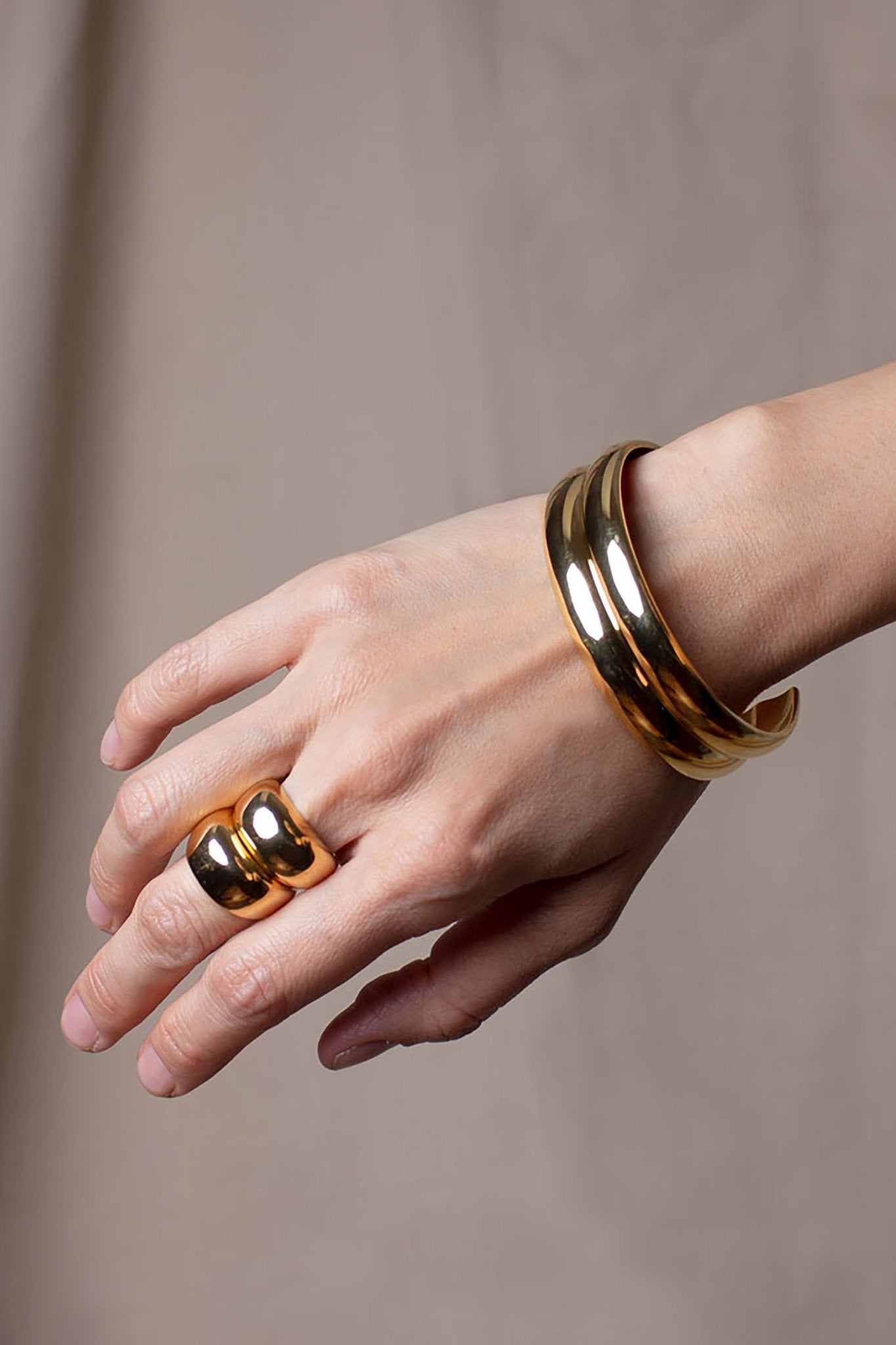 Two Golden Dome Rings stacked on a female models middle finger