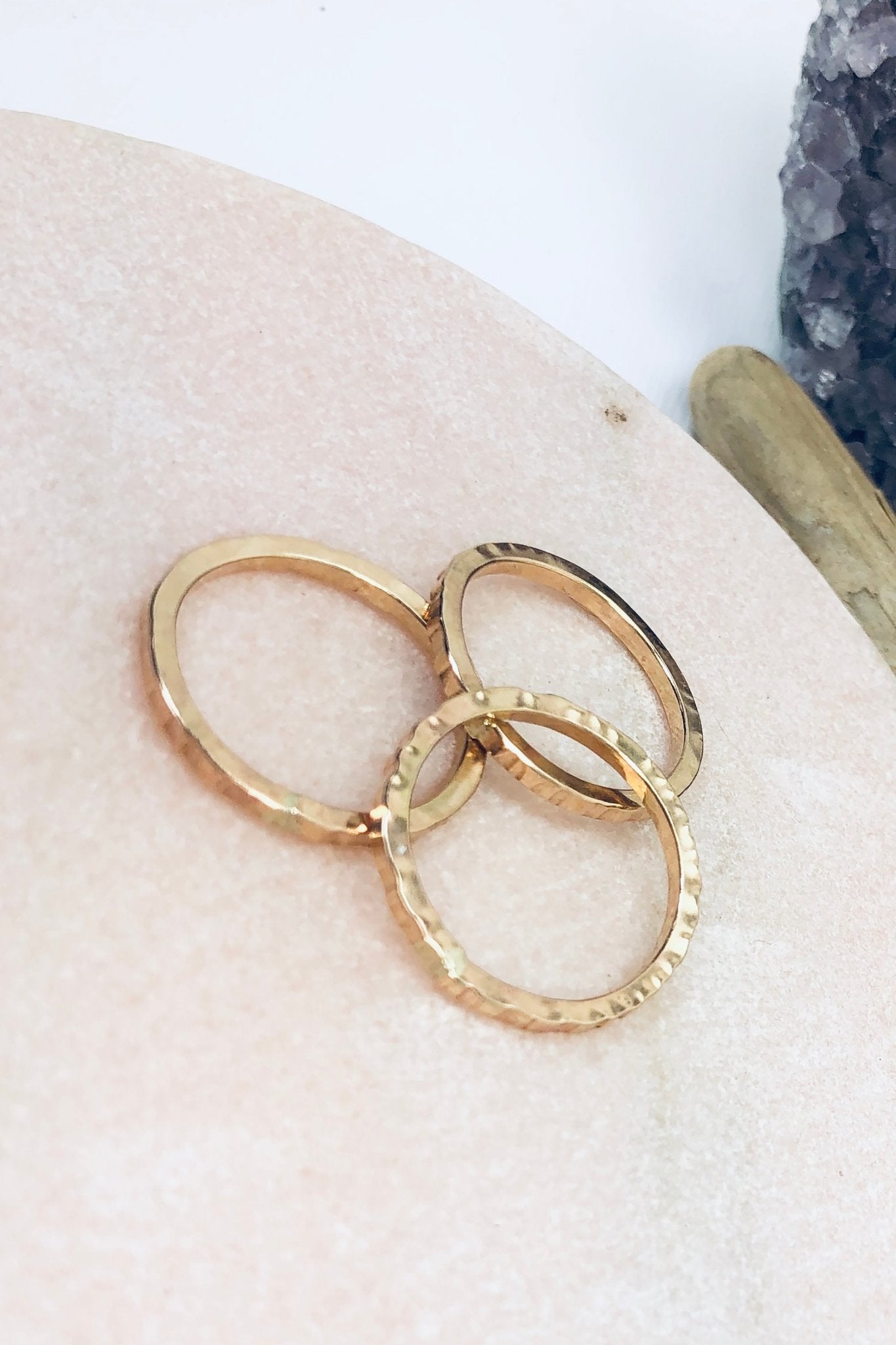 Golden Stacking Rings laying in a wooden table - L'Atelier Global